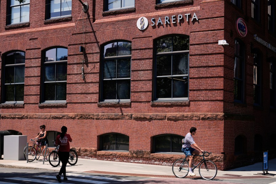 A cyclist passes the headquarters of Sarepta Therapeutics , Monday, July 28, 2025, in Cambridge, Mass. (AP Photo/Charles Krupa)