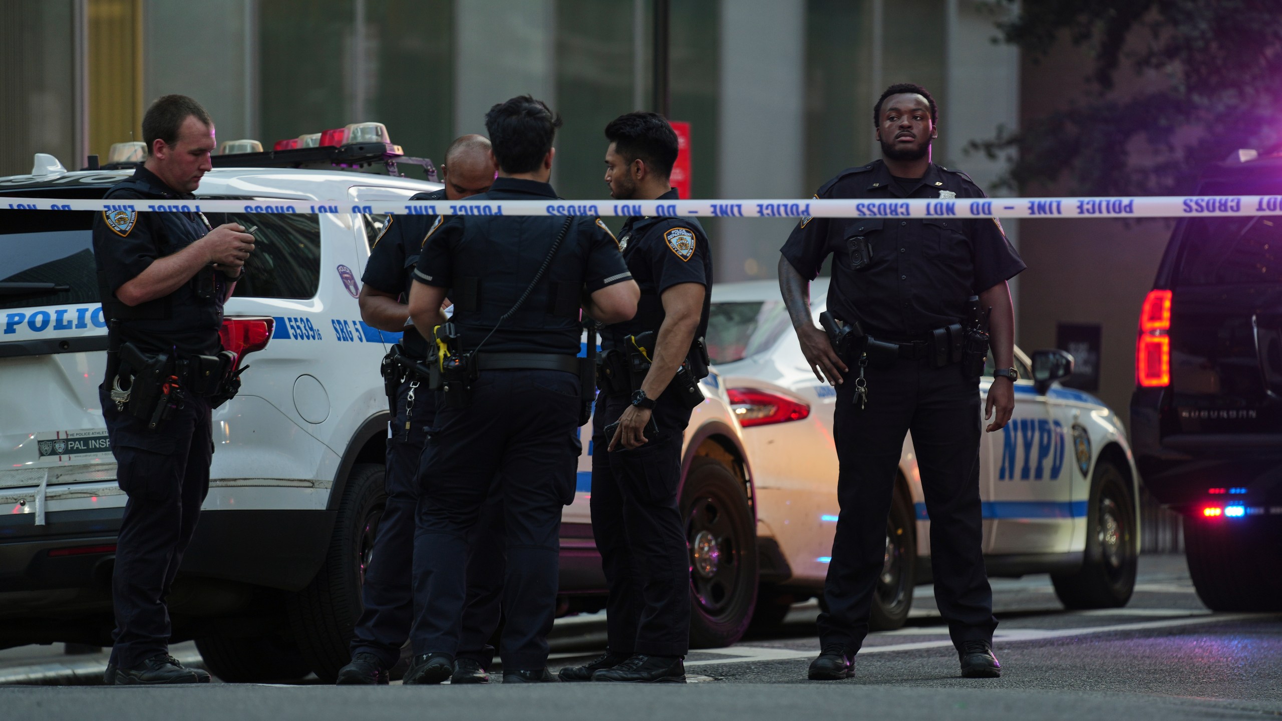 A New York Police officers gather at the scene on 52nd Street outside a Manhattan office building where two people were shot, including a New York police officer, Monday, July 28, 2025, in New York. (AP Photo/Angelina Katsanis)