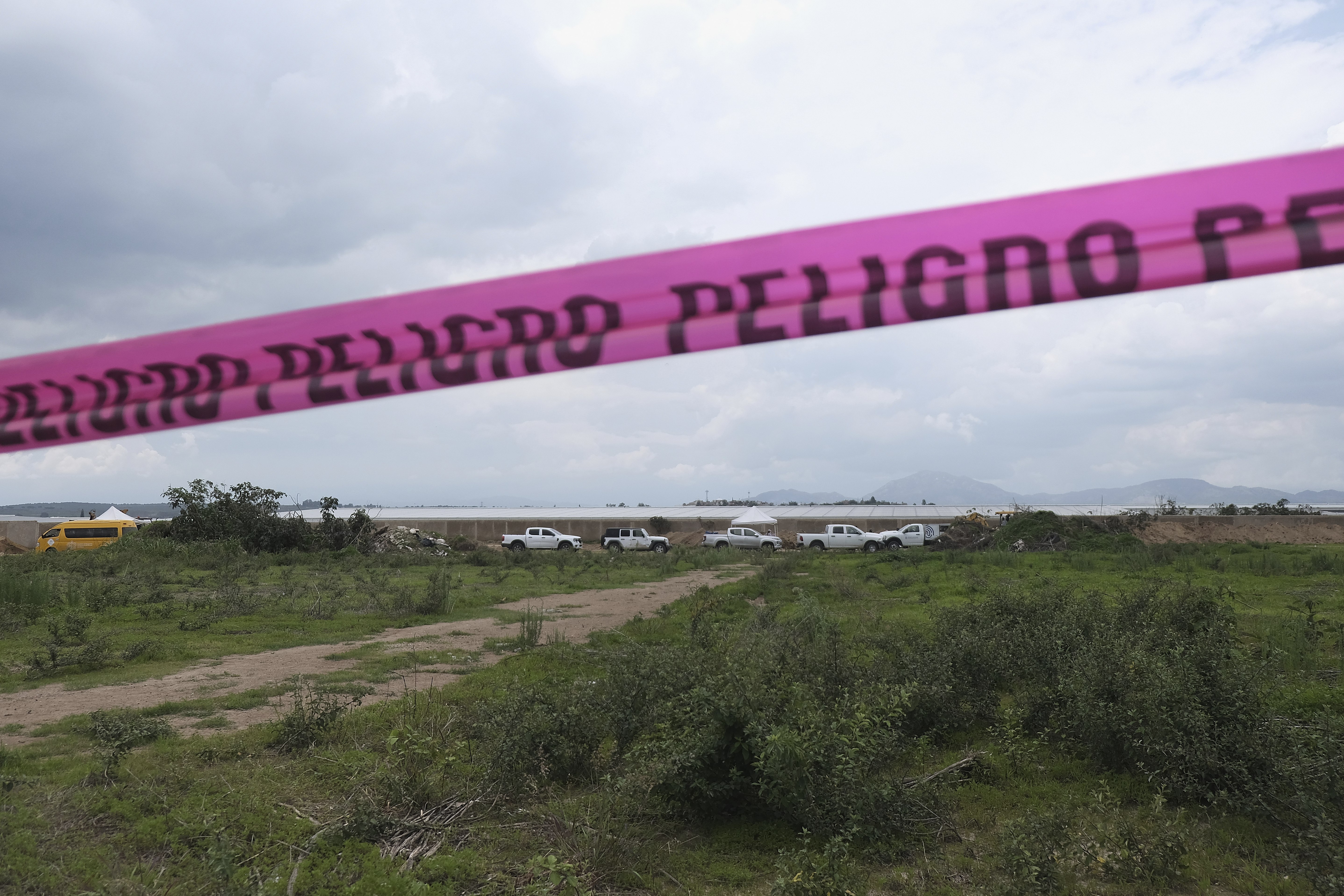 Danger warning tape streches along a Nextipac ranch where prosecutors say bodies were discovered in a mass grave during excavations for the construction, in the Zapopan municipality, Jalisco state, Mexico, Friday, July 11, 2025. (AP Photo/Alejandra Leyva)