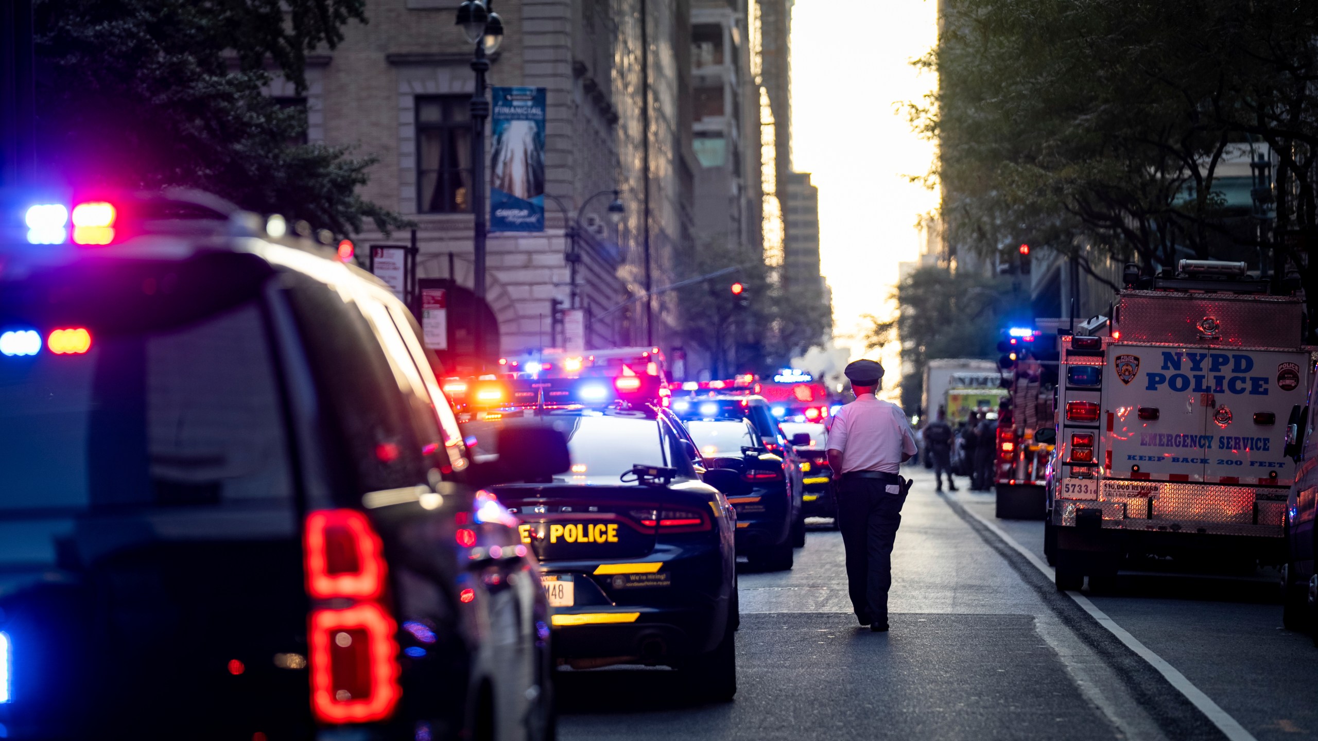 A New York police officer stands watch on 52nd Street outside a Manhattan office building where at least two people were shot, including a police officer, Monday, July 28, 2025, in New York. (AP Photo/Angelina Katsanis)