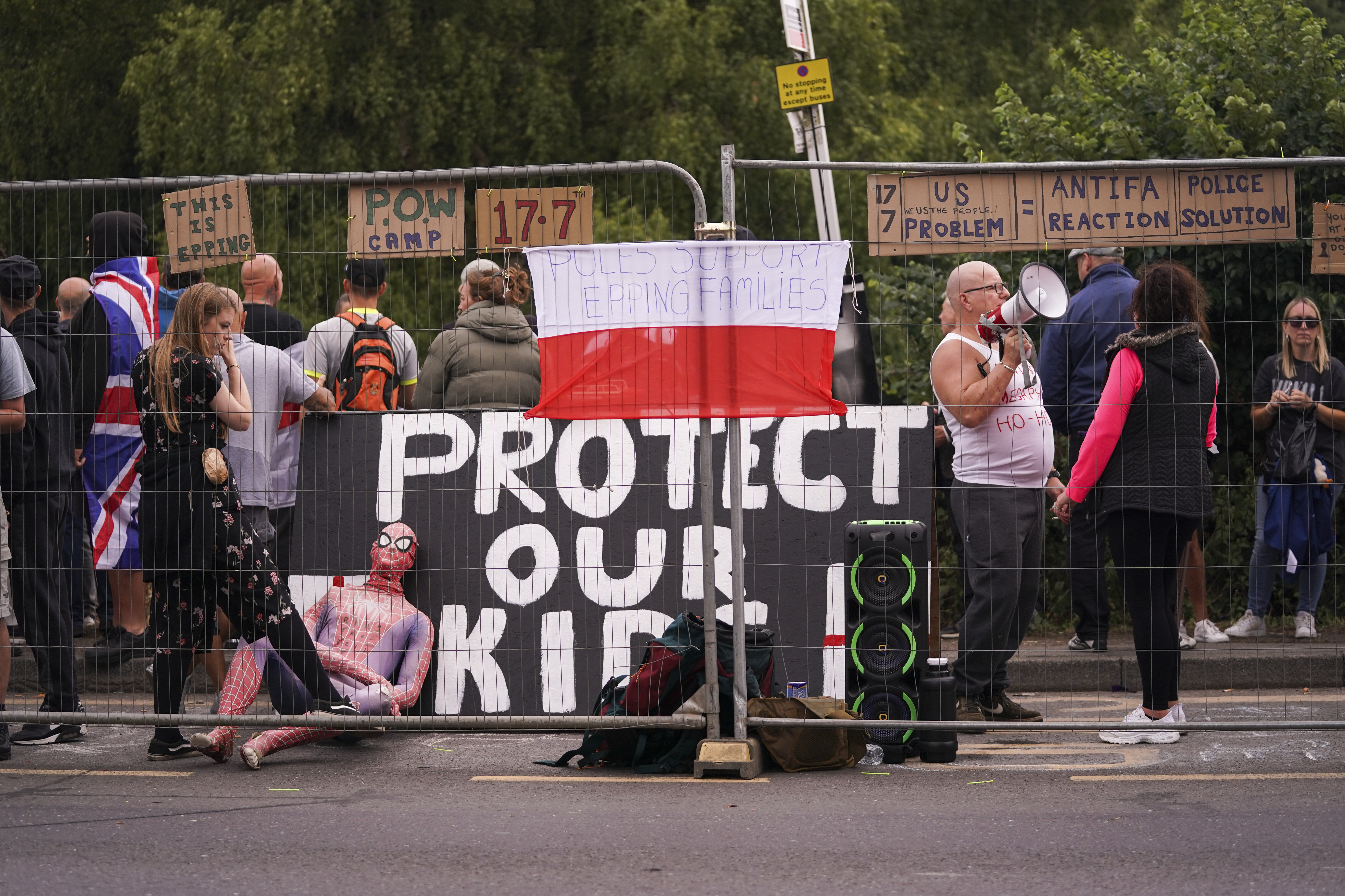 Demonstrators hold flags and placards as they stand outside the Bell Hotel in Epping, near London, Sunday, July 27, 2025.(AP Photo/Alberto Pezzali)
