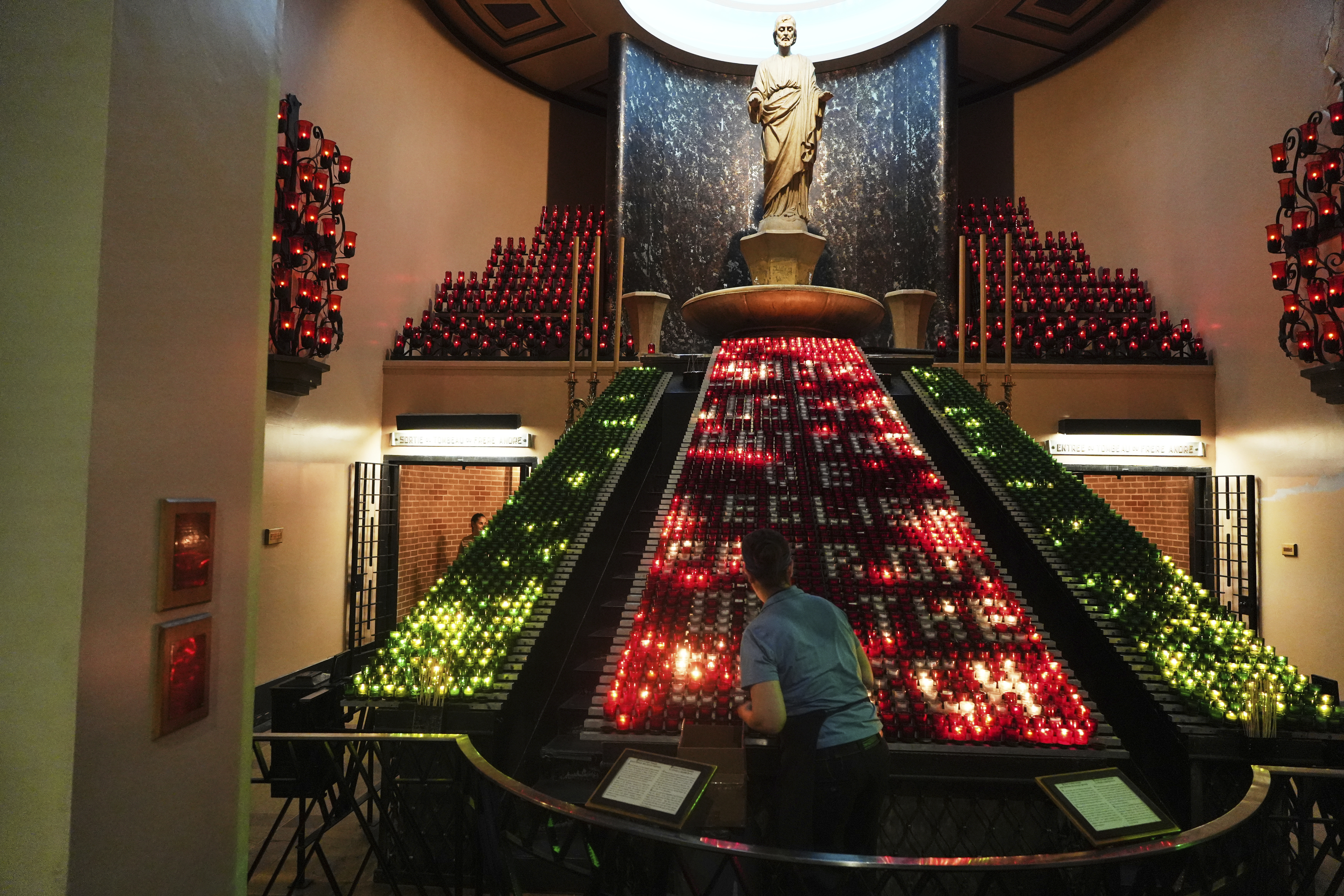 A worker arranges candles inside the Votive Chapel at the national shrine of Saint Joseph's Oratory of Mount Royal, in Montreal, Saturday, June 28, 2025. (AP Photo/Luis Andres Henao)