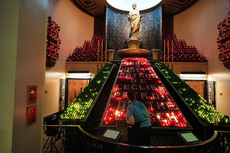 A worker arranges candles inside the Votive Chapel at the national shrine of Saint Joseph's Oratory of Mount Royal, in Montreal, Saturday, June 28, 2025. (AP Photo/Luis Andres Henao)