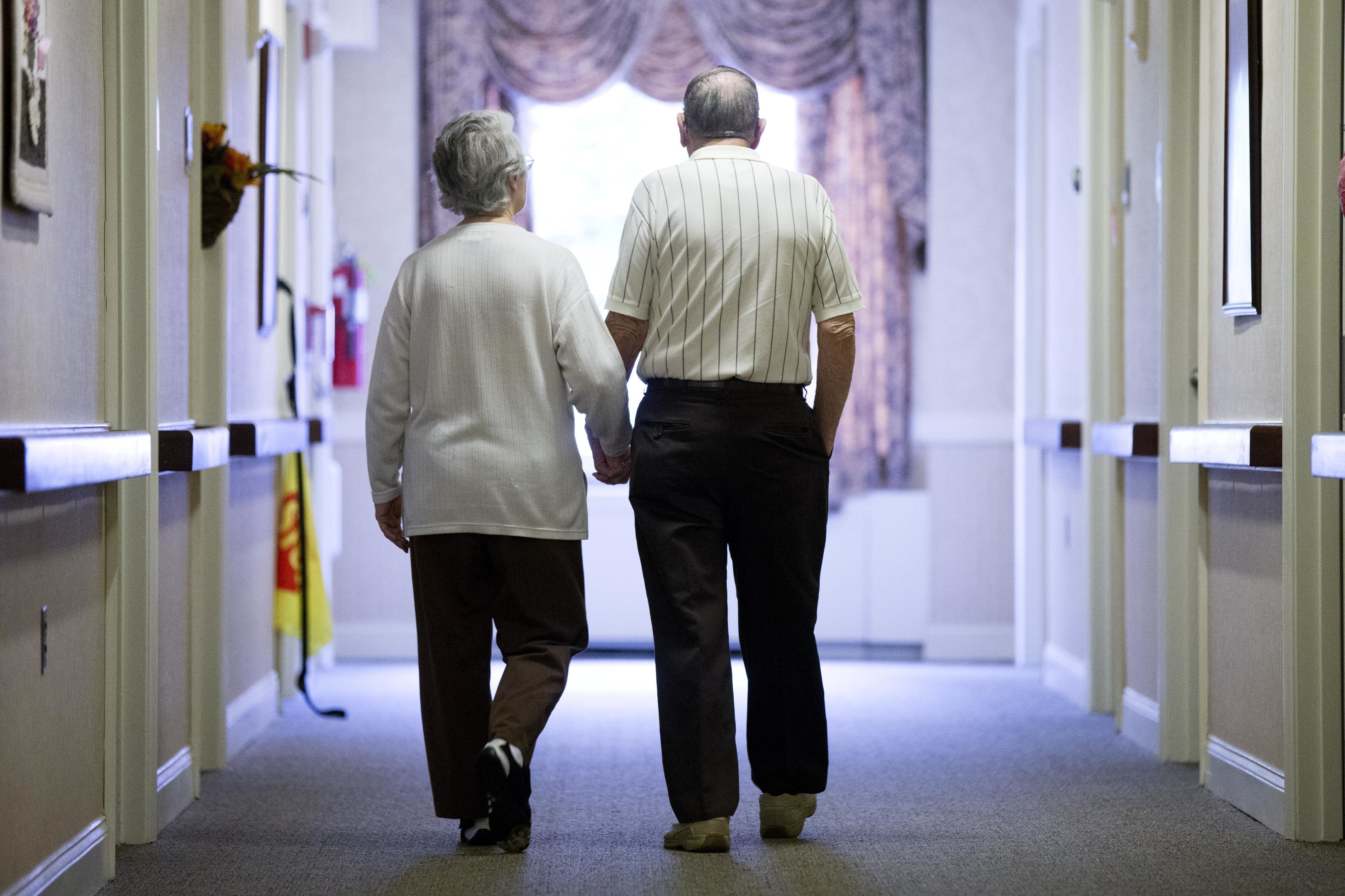 FILE - An elderly couple walks down a hallway in Easton, Pa., on Nov. 6, 2015. (AP Photo/Matt Rourke, File)