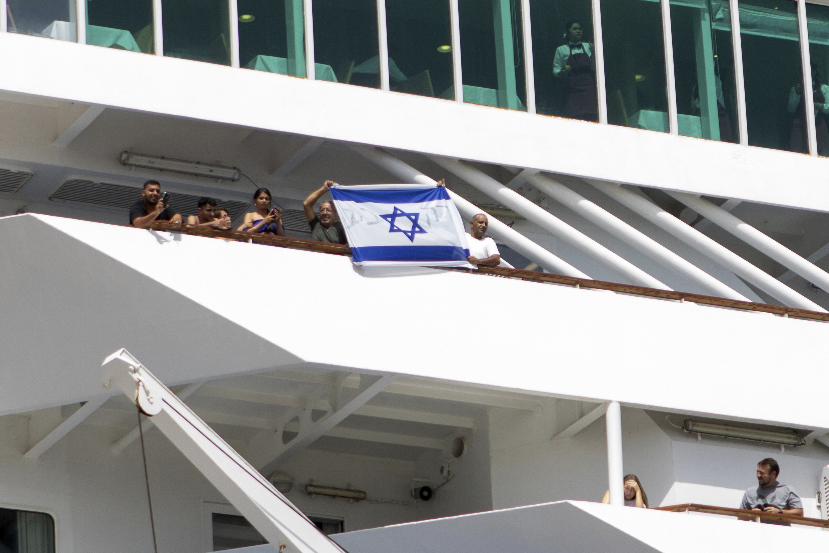 Two men hold up an Israeli flag during the departure of a cruise ship carrying Israeli tourists on the southeastern Aegean Sea island of Rhodes, Greece, Monday, July 28, 2025. (InTime News via AP)