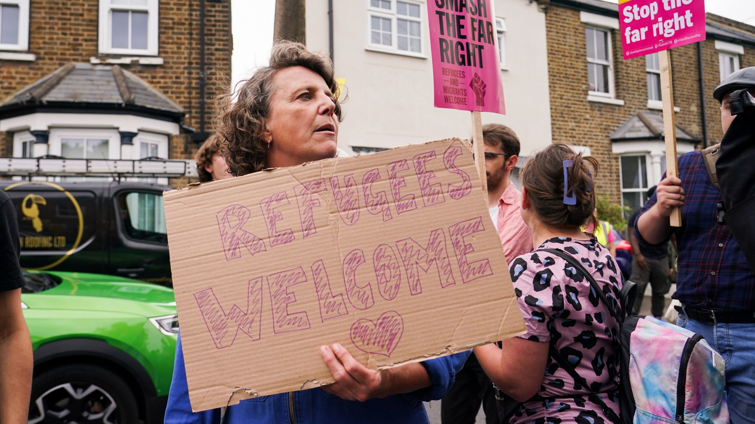 A demonstrator holds a placard as she leaves a protest outside the Bell Hotel in Epping, near London, Sunday, July 27, 2025.(AP Photo/Alberto Pezzali)