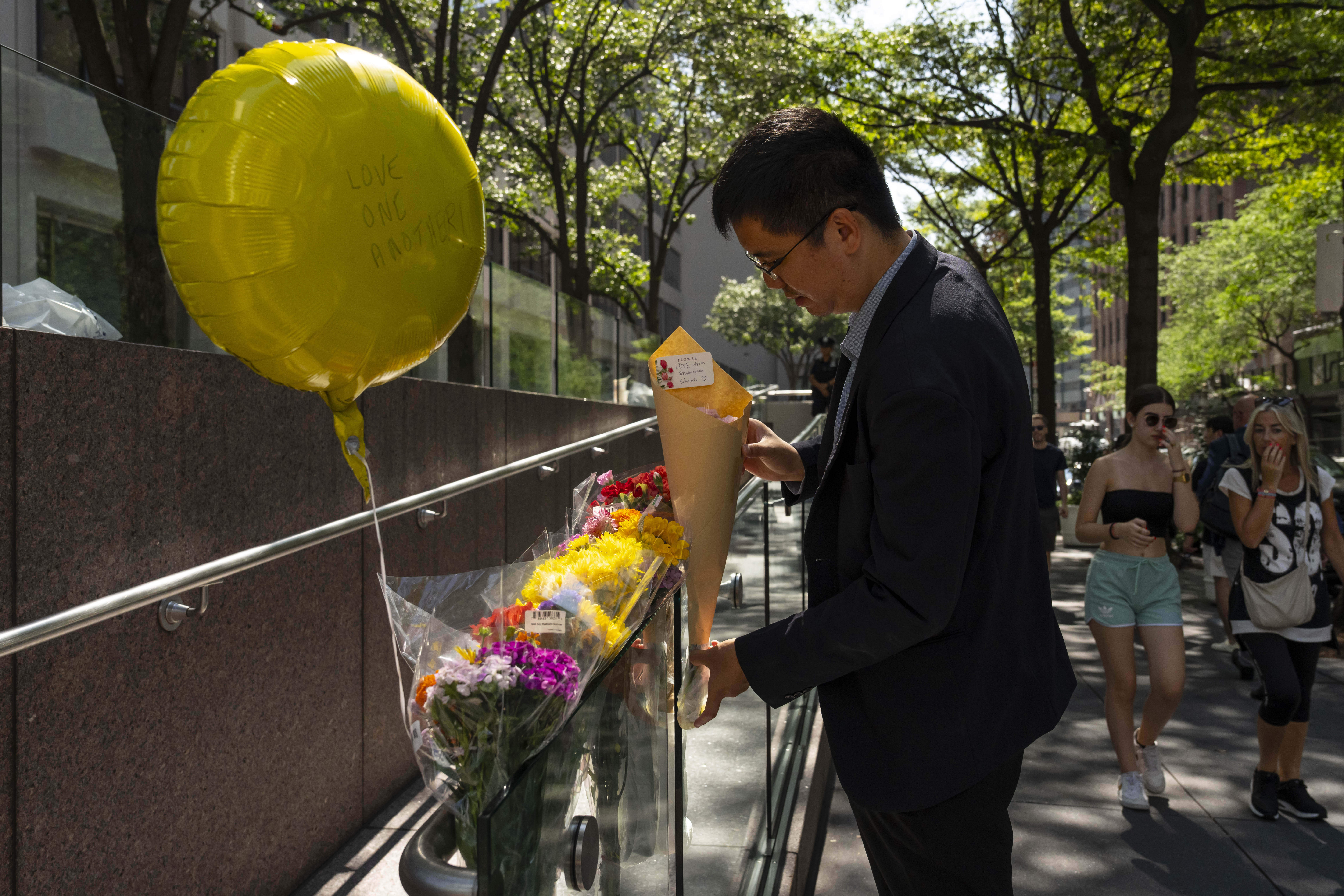 A person leaves flowers at a make shift memorial outside scene of Monday's deadly shooting, Tuesday, July 29, 2025, in New York. (AP Photo/Yuki Iwamura)