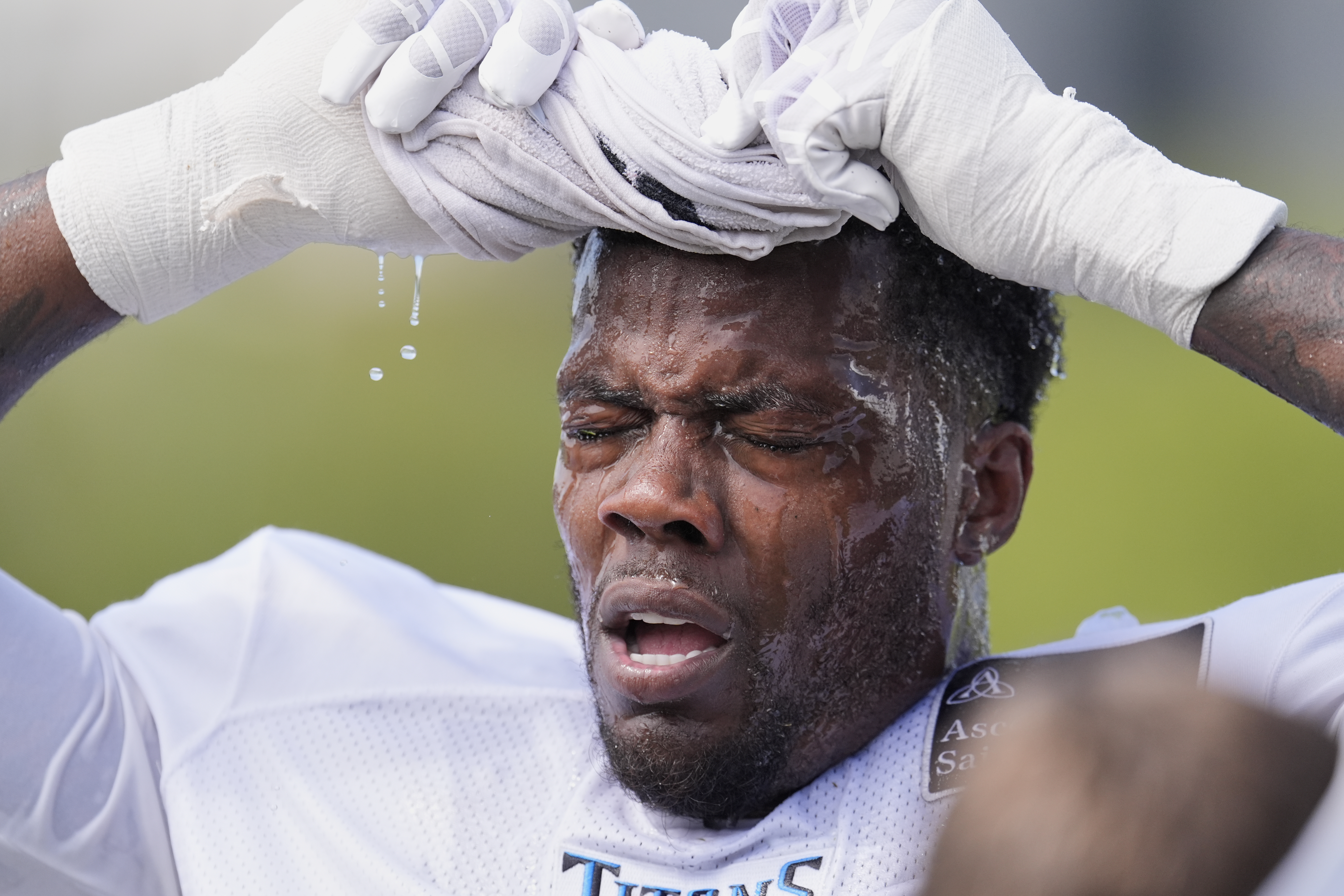 Tennessee Titans linebacker Arden Key uses a wet towel to cool off after practice at the team's NFL football training camp Tuesday, July 29, 2025, in Nashville, Tenn. (AP Photo/George Walker IV)