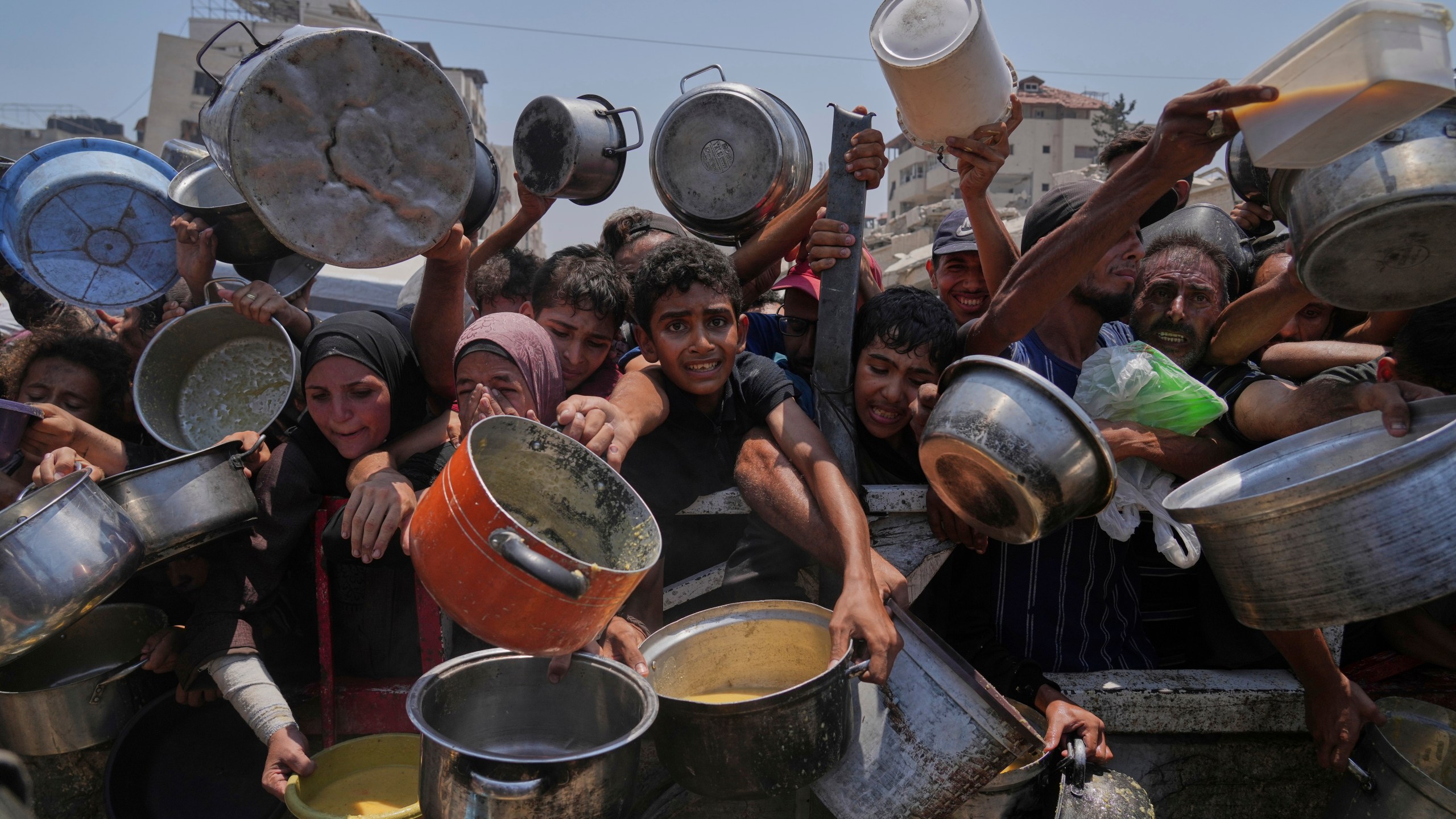 Palestinians struggle to get donated food at a community kitchen, in Gaza City, northern Gaza Strip, Saturday, July 26, 2025. (AP Photo/Abdel Kareem Hana)