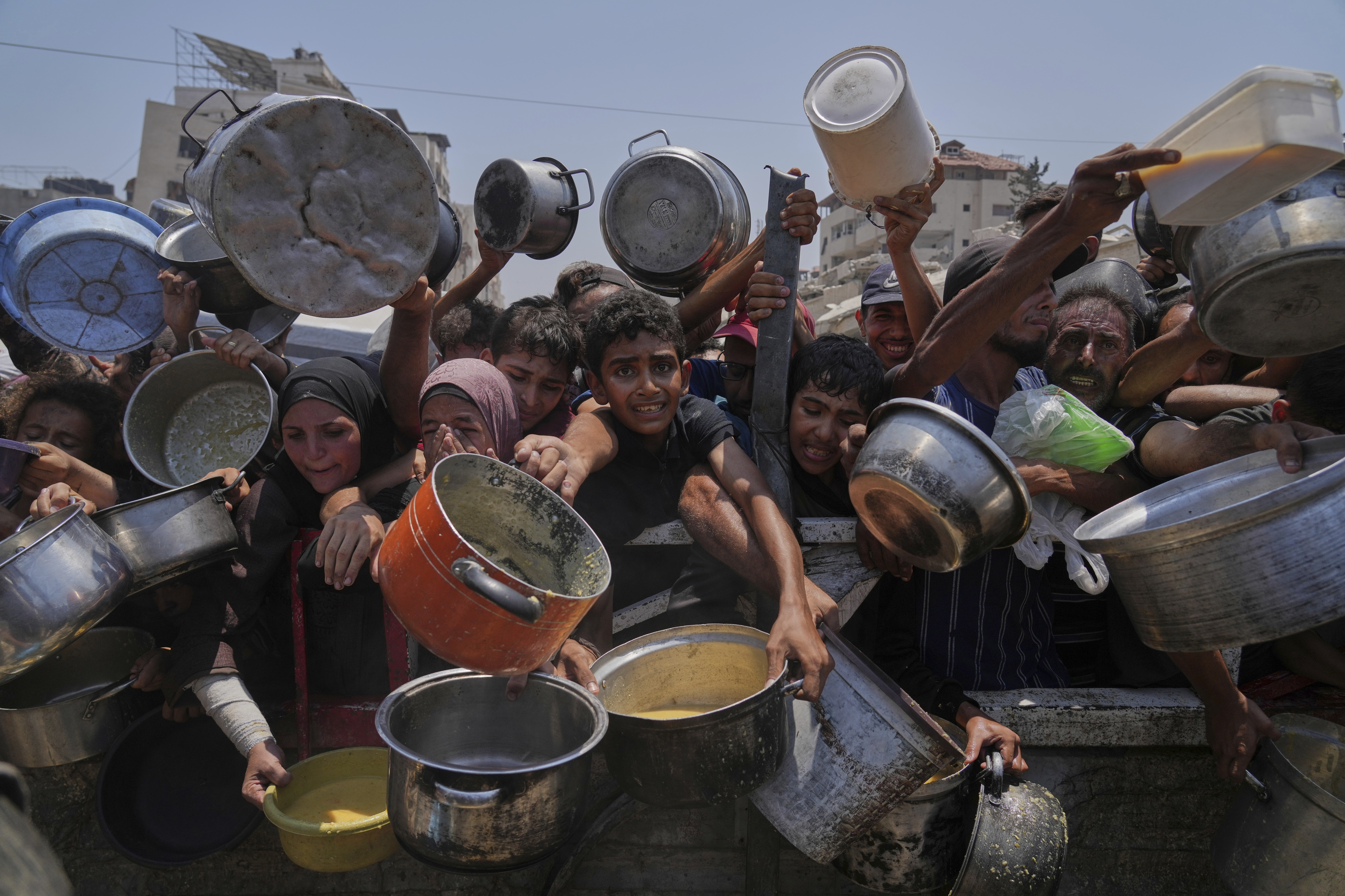 Palestinians struggle to get donated food at a community kitchen, in Gaza City, northern Gaza Strip, Saturday, July 26, 2025. (AP Photo/Abdel Kareem Hana)