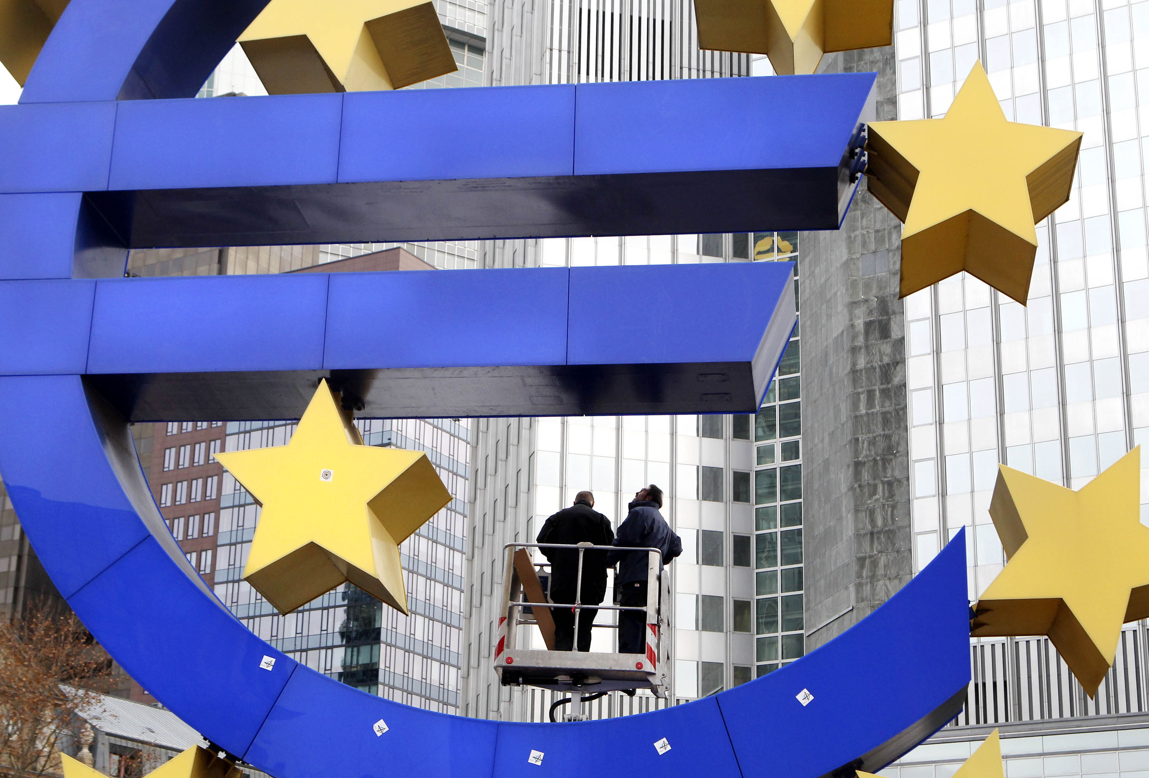 FILE -Workers change tube lights of the Euro sculpture in front of the European Central Bank in Frankfurt, Germany, Dec.6, 2011. (AP Photo/Michael Probst, File)