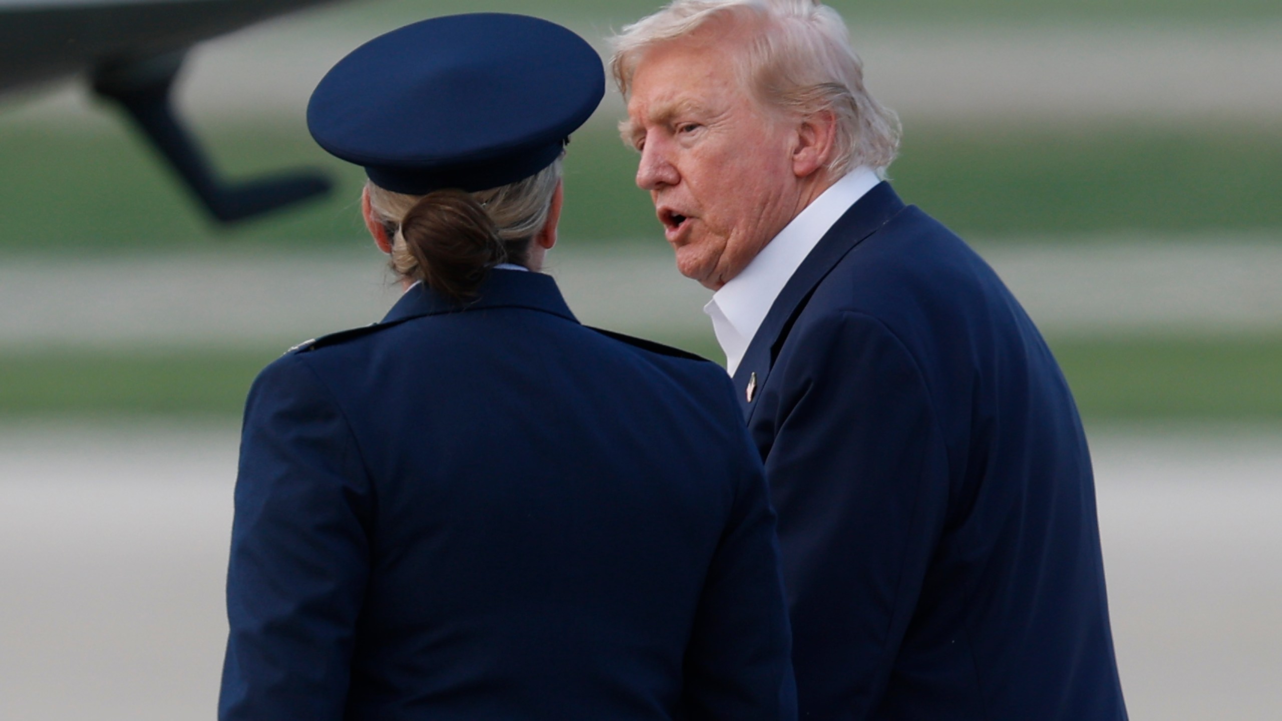 President Donald Trump, right, is escorted by Air Force 89th Air Wing Deputy Commander Melissa Dombrock, left, as he walks from Air Force One before boarding Marine One, upon his arrival at Joint Base Andrews, Md., Tuesday, July 29, 2025. (AP Photo/Luis M. Alvarez)