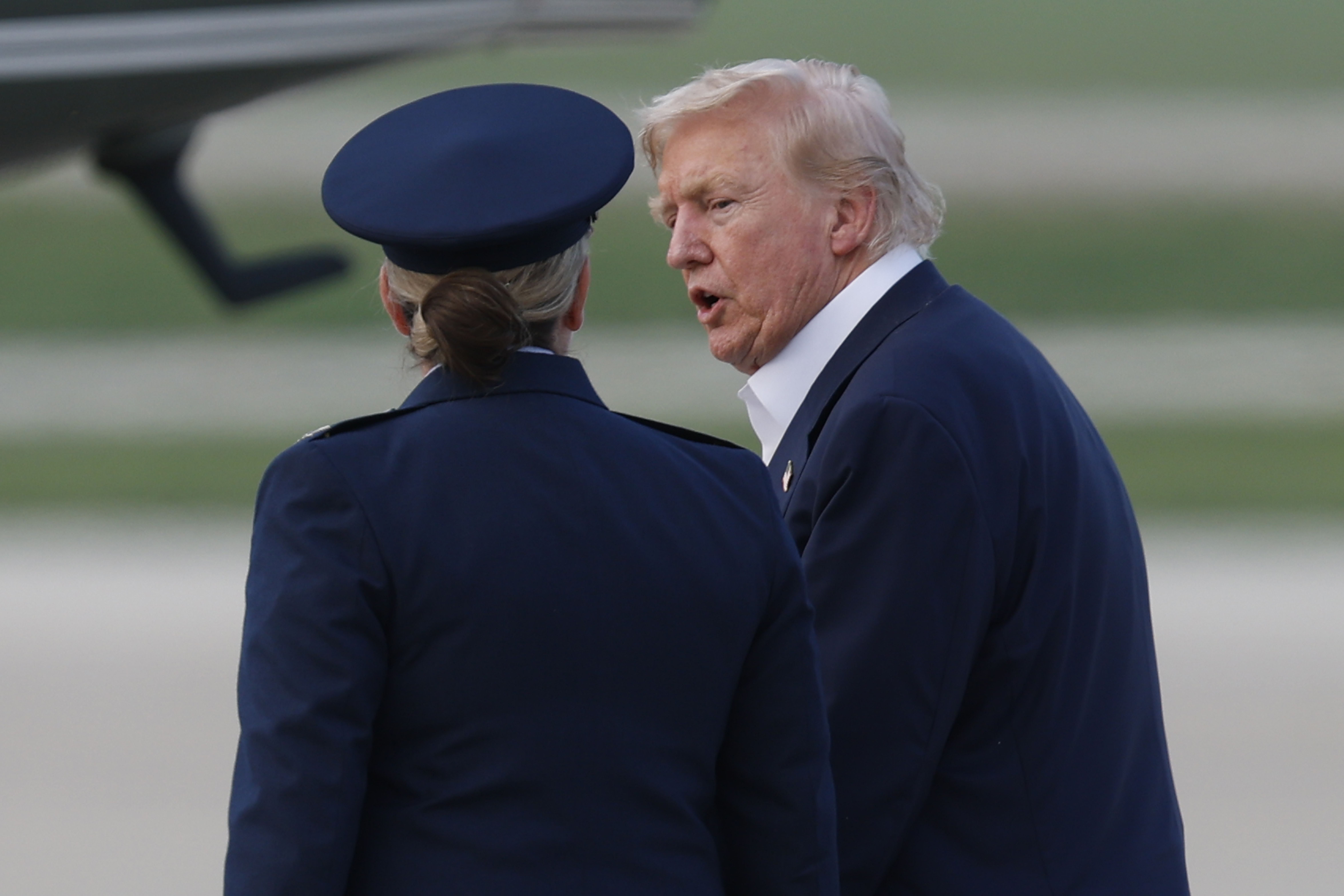 President Donald Trump, right, is escorted by Air Force 89th Air Wing Deputy Commander Melissa Dombrock, left, as he walks from Air Force One before boarding Marine One, upon his arrival at Joint Base Andrews, Md., Tuesday, July 29, 2025. (AP Photo/Luis M. Alvarez)