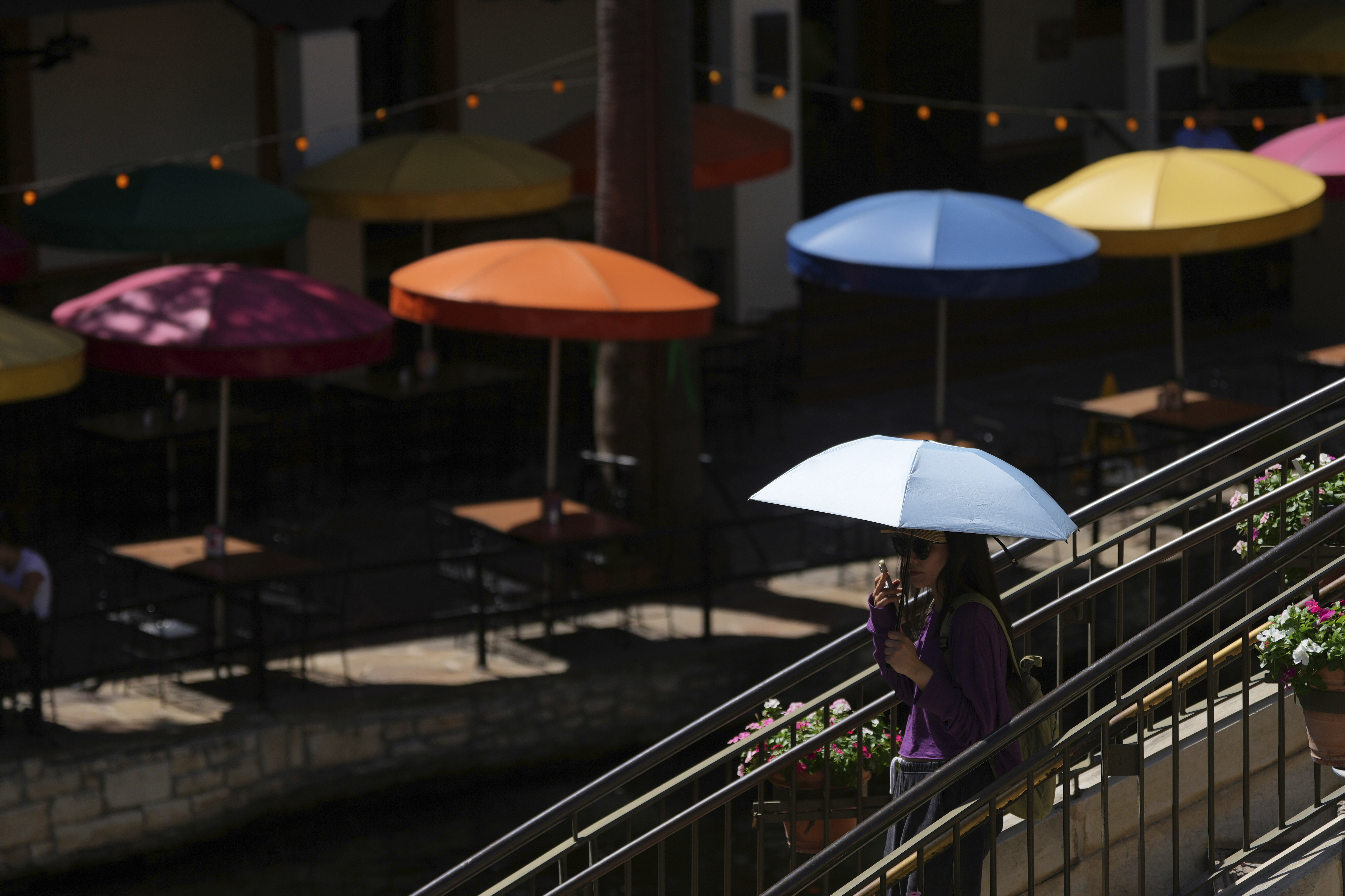 A visitor uses an umbrella to shield the sun, Tuesday, July 29, 2025, in San Antonio. (AP Photo/Eric Gay)