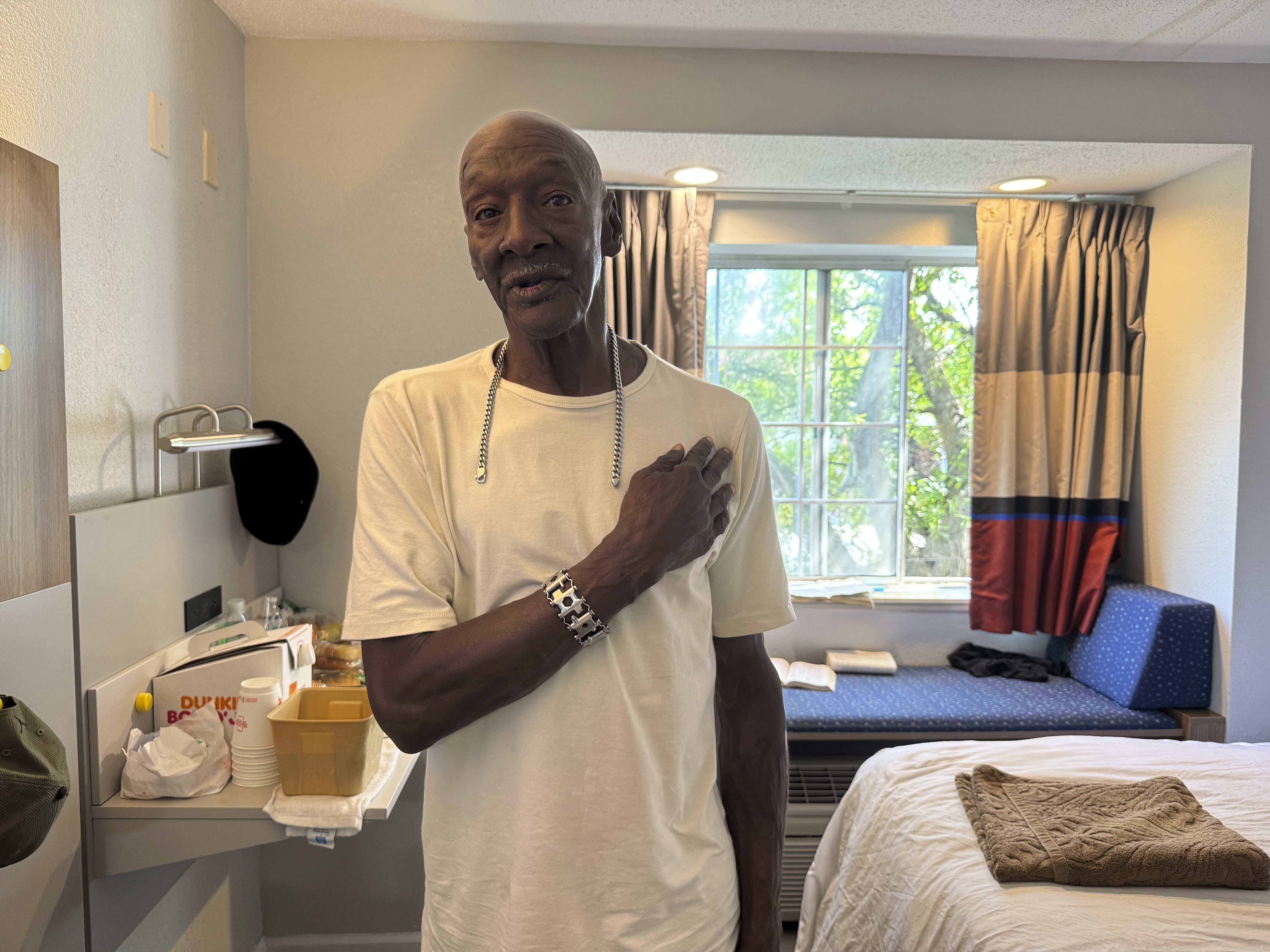 Allen Hall, 71, poses for a photo in his room at a hotel in Atlanta, Wednesday, July 23, 2025, with a bracelet and chain given to him by Cornelius Taylor, who died after he was crushed by a bulldozer at a homeless encampment in January. (AP Photo/Charlotte Kramon)