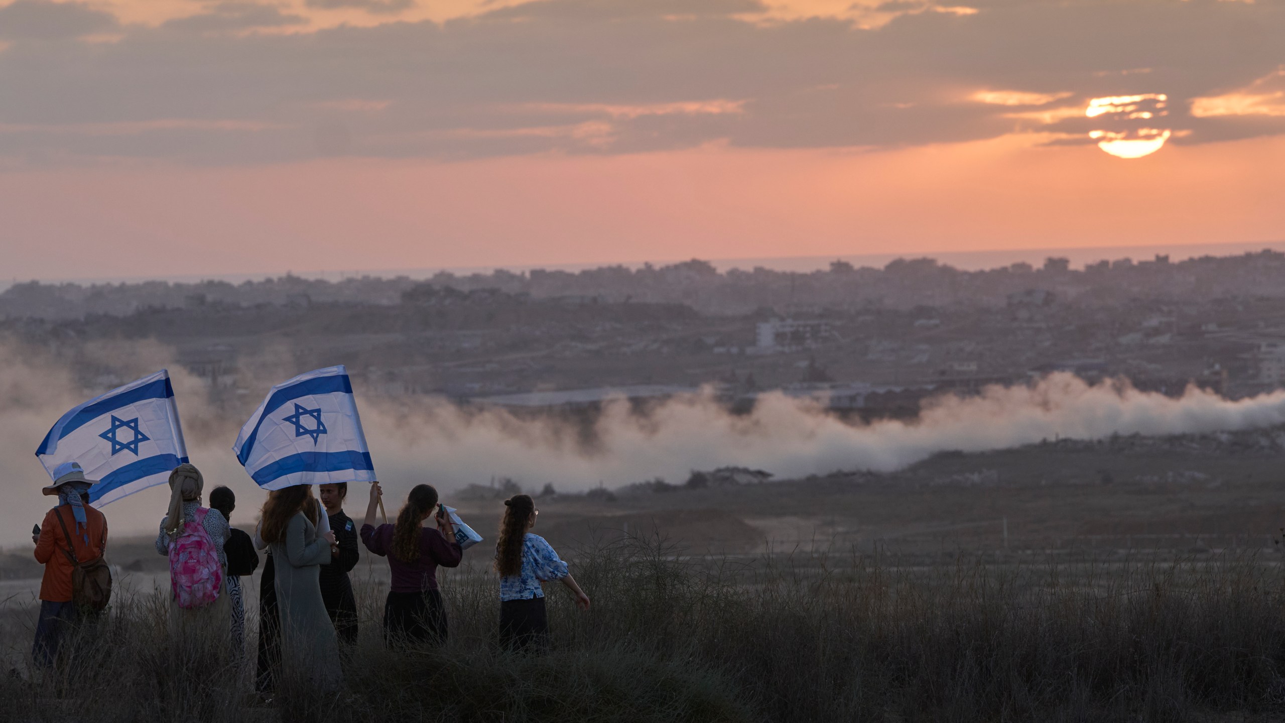 Israeli right-wing activists watch the northern Gaza Strip during a rally calling for the re-establishment of Jewish settlements in the Gaza Strip, near the border in southern Israel, Wednesday, July 30, 2025. (AP Photo/Ohad Zwigenberg)