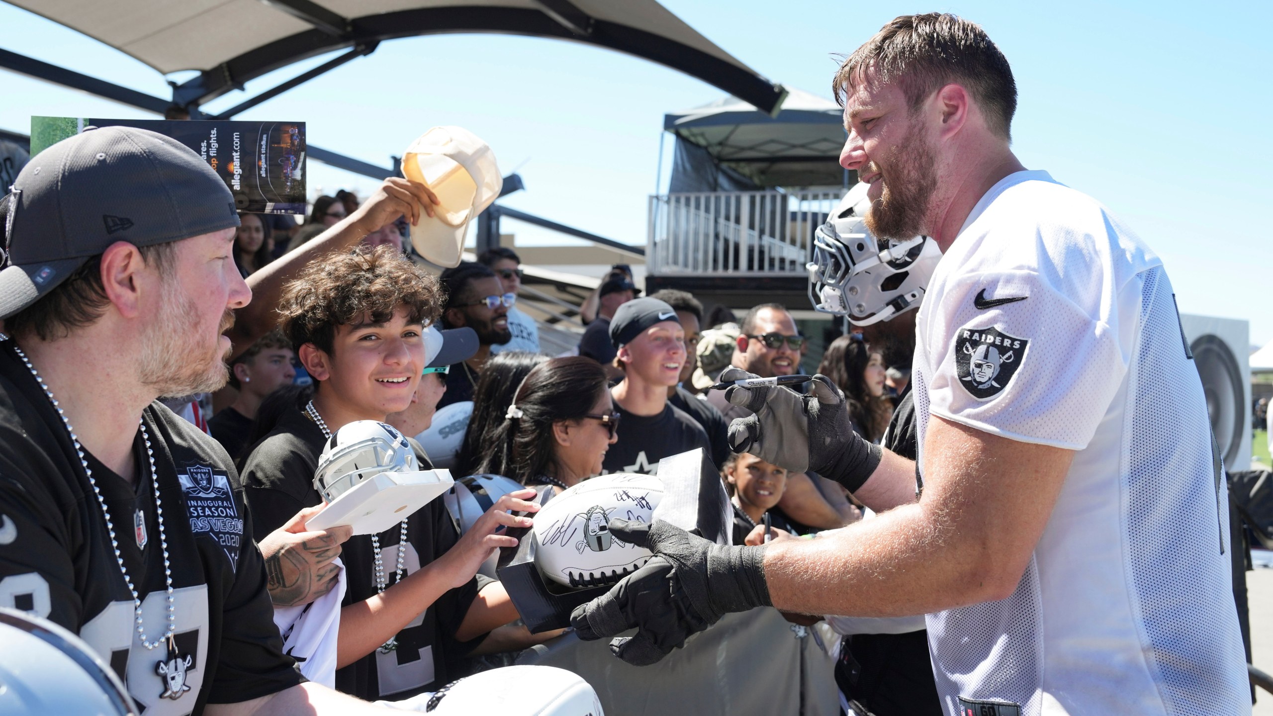 Las Vegas Raiders offensive tackle Kolton Miller, right, gives autographs after the team's NFL football training camp, Sunday, July 27, 2025, in Henderson, Nev. (AP Photo/Candice Ward)