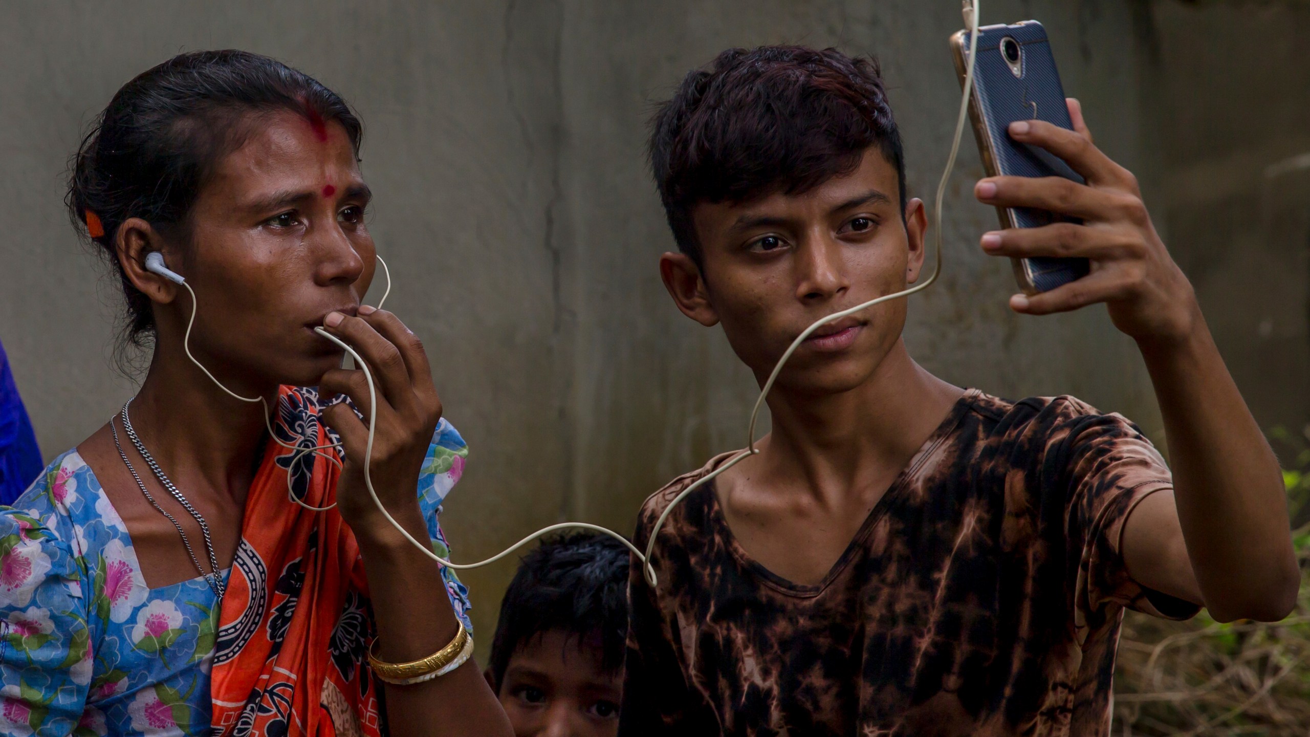 FILE - Sarasvati Devi talks to her mother in Myanmar via video call as Ranjan, her brother, holds the phone, outside a camp for Hindu refugees near Kutupalong, Bangladesh, Sept. 26, 2017. (AP Photo/Dar Yasin, File)