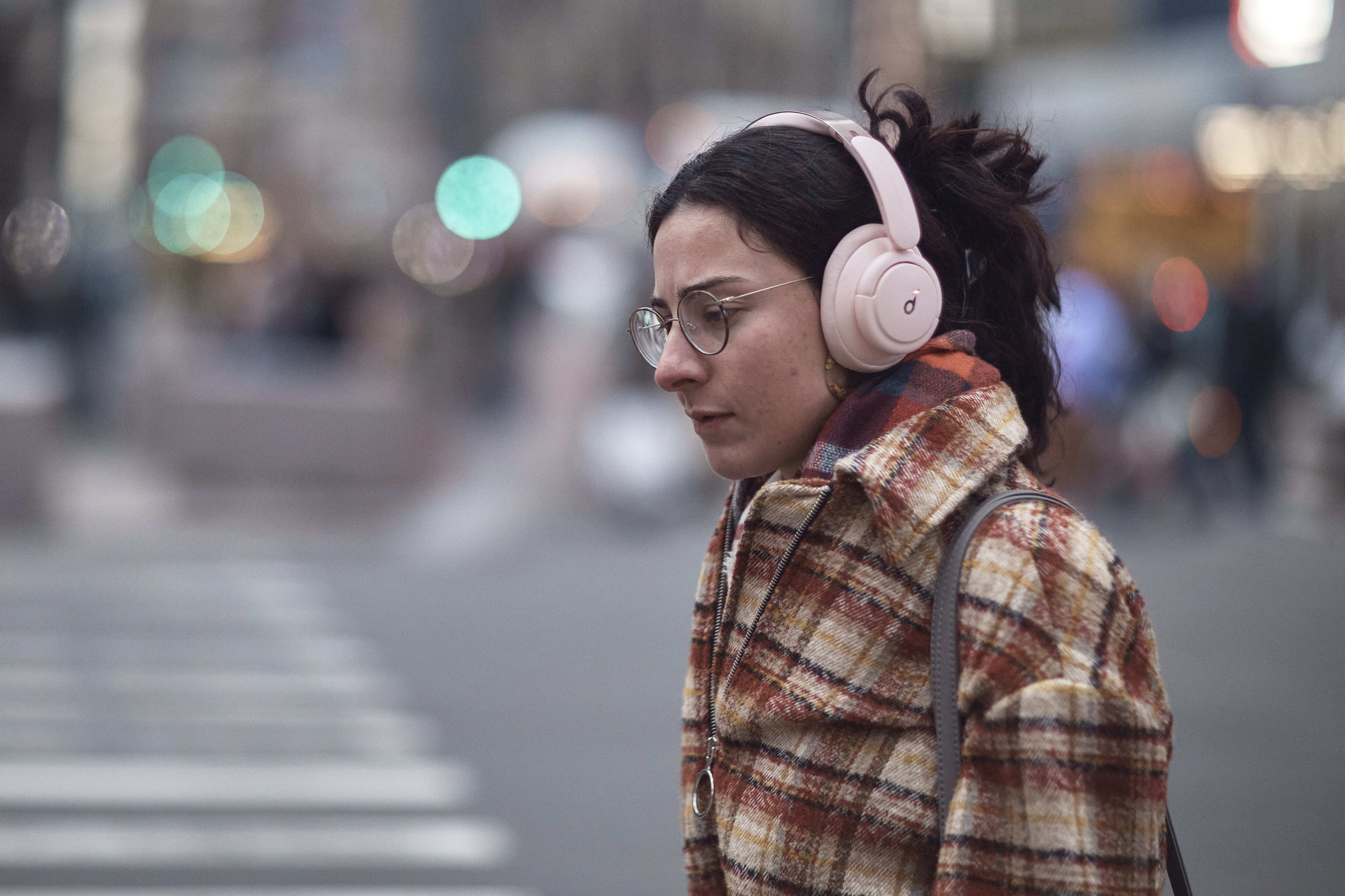 FILE - A woman walks using her headphones on Tuesday, Jan. 17, 2023, in New York. (AP Photo/Andres Kudacki, File)