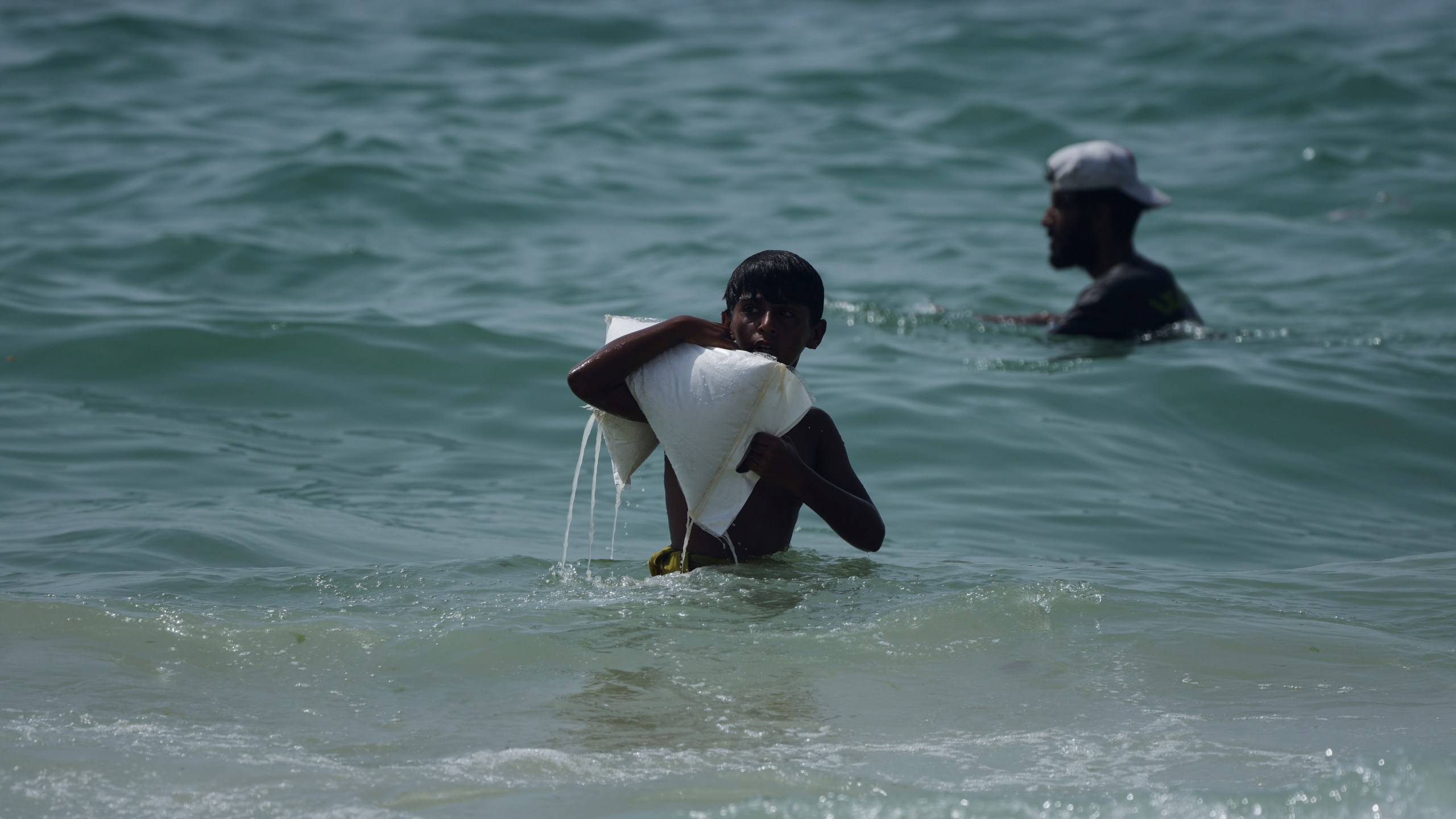 FILE - A Palestinian youth carries a sack of aid that landed in the Mediterranean Sea after being airdropped over central Gaza, Gaza Strip Tuesday, July 29, 2025. (AP Photo/Abdel Kareem Hana, File)