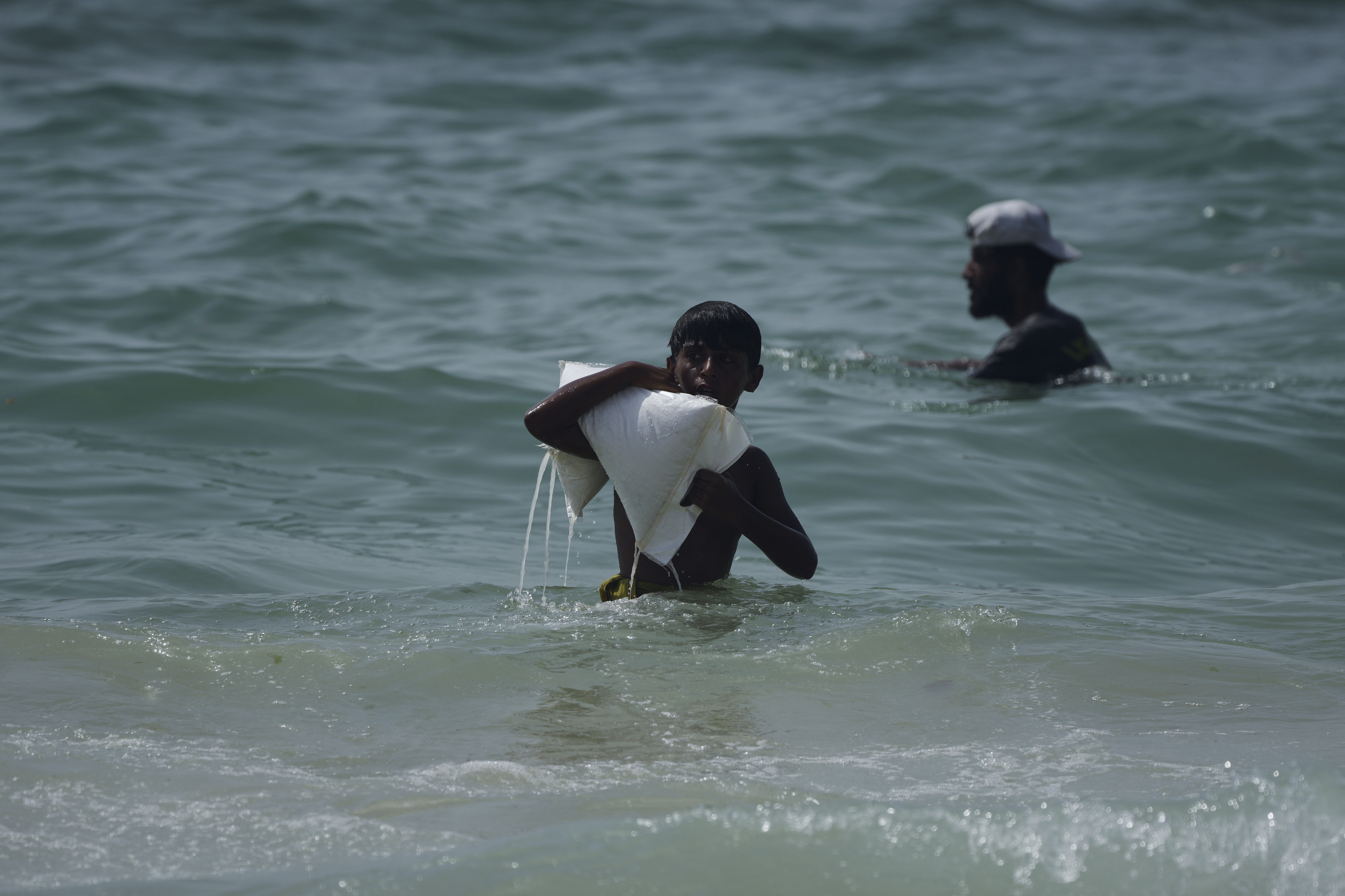 FILE - A Palestinian youth carries a sack of aid that landed in the Mediterranean Sea after being airdropped over central Gaza, Gaza Strip Tuesday, July 29, 2025. (AP Photo/Abdel Kareem Hana, File)