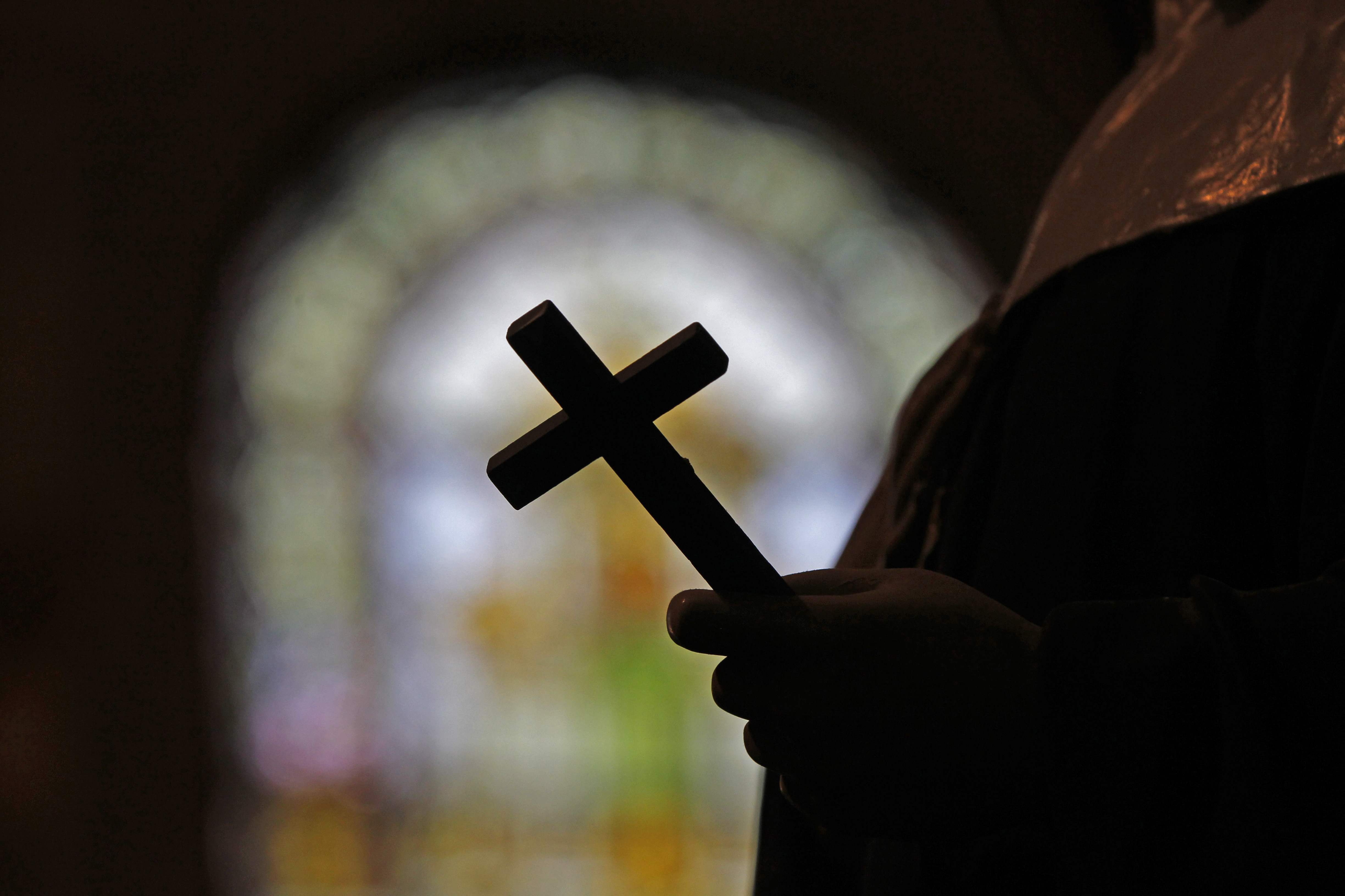 FILE - A crucifix is silhouetted against a stained glass window inside a Catholic Church in New Orleans, Dec. 1, 2012. (AP Photo/Gerald Herbert, File)