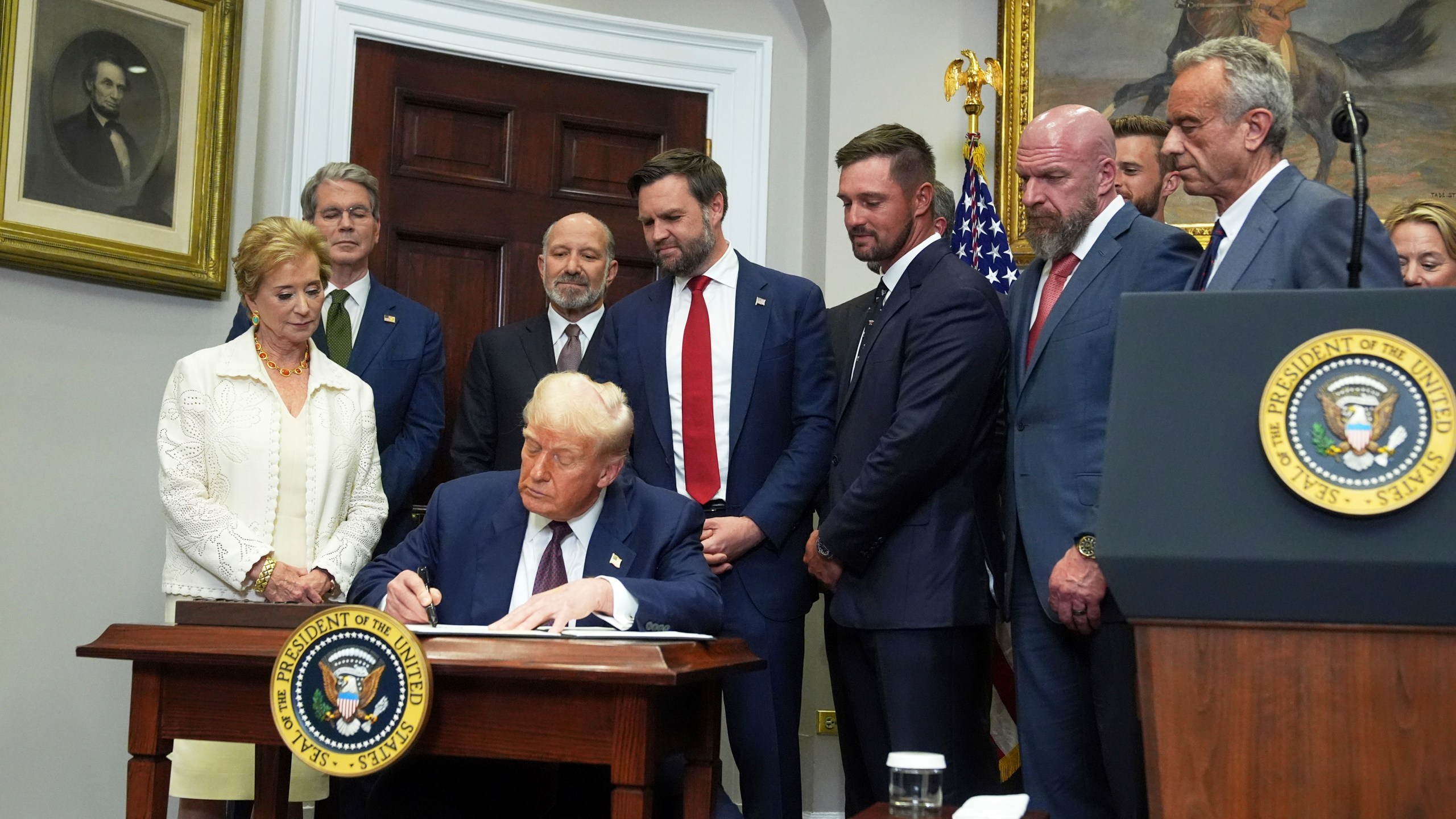 President Donald Trump signs an executive order restarting the Presidential Fitness Test in public schools as Secretary of Education Linda McMahon, from left, Treasury Secretary Scott Bessent, Commerce Secretary Howard Lutnick, Vice President JD Vance, professional golfer Bryson DeChambeau, WWE CCO Triple H and Health and Human Services Secretary Robert F. Kennedy Jr. watch, Thursday, July 31, 2025, in the Roosevelt Room of the White House in Washington. (AP Photo/Jacquelyn Martin)