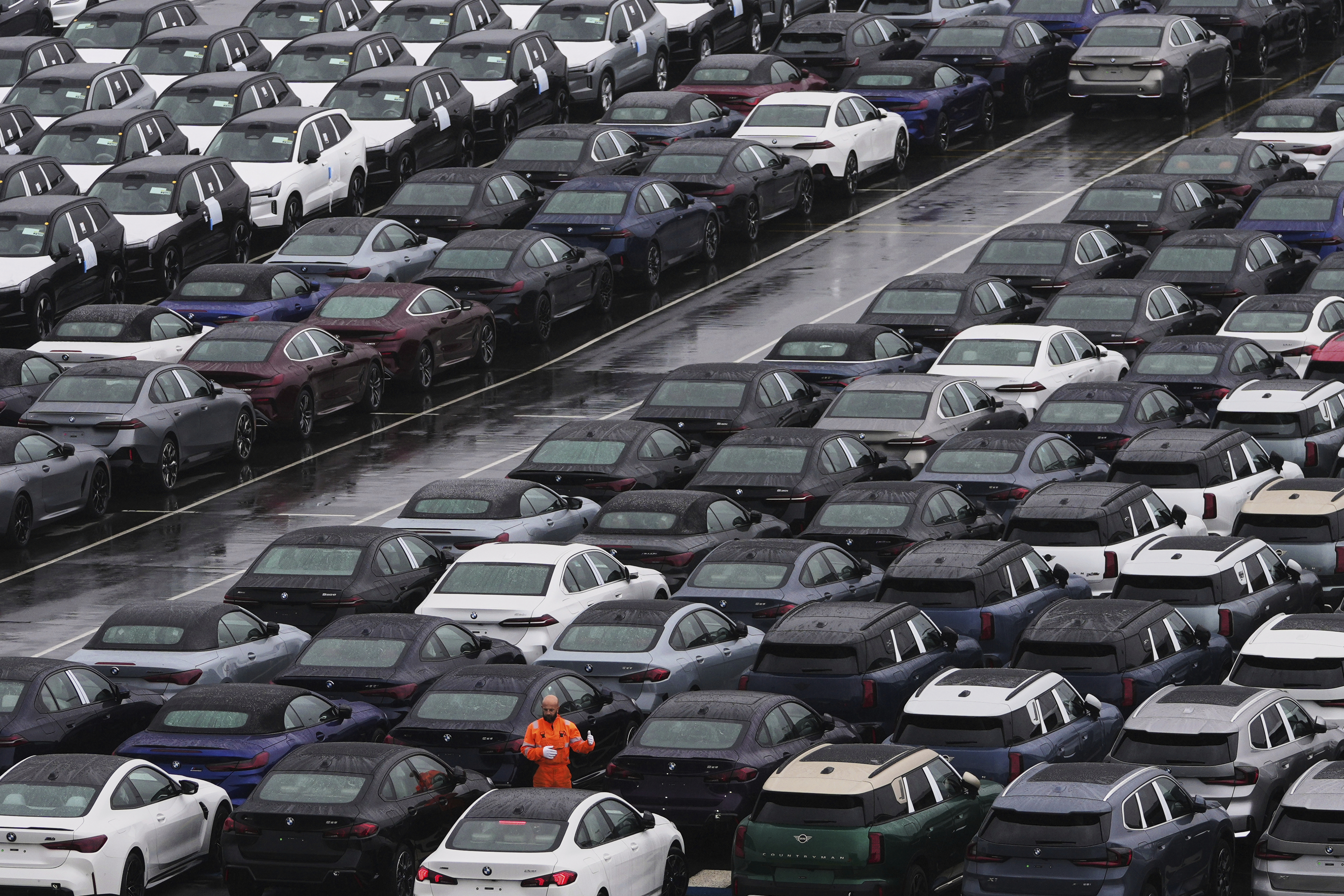 A worker checks on new cars parked in a lot at the International Car Operators terminal in the Port of Zeebrugge, Belgium, Thursday, July 31, 2025. (AP Photo/Virginia Mayo)