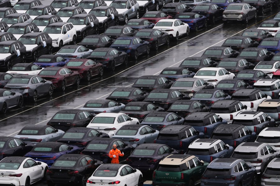 A worker checks on new cars parked in a lot at the International Car Operators terminal in the Port of Zeebrugge, Belgium, Thursday, July 31, 2025. (AP Photo/Virginia Mayo)