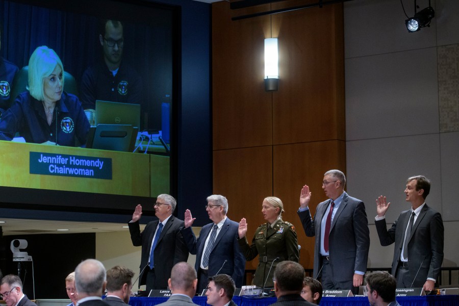 National Transportation Safety Board Chairwoman Jennifer Homendy, on monitor left, swears-in the witnesses from left: Dan Cooper, Sikorsky Aircraft, Lance Gant, Federal Aviation Administration, U.S. Army CW4 Kylene Lewis, Steve Braddom, U.S. Army, and Scott Rosengren, U.S. Army, during the NTSB fact-finding hearing on the DCA midair collision accident, at the National Transportation and Safety Board boardroom, Wednesday, July 30, 2025, in Washington. (AP Photo/Rod Lamkey, Jr.)