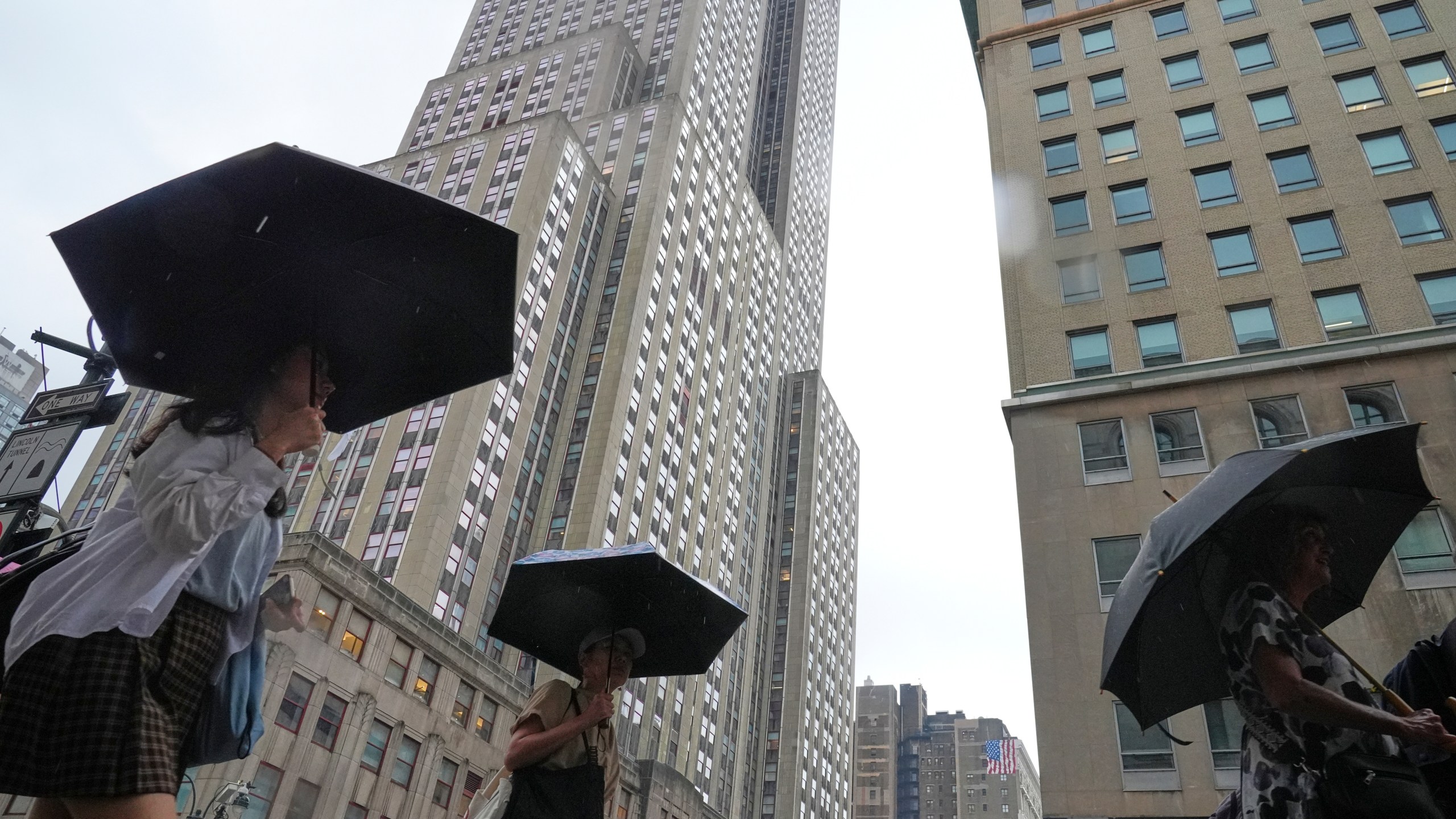 Pedestrians use umbrellas as they pass the Empire State Building during a rain storm Thursday, July 31, 2025, in New York. (AP Photo/Frank Franklin II)