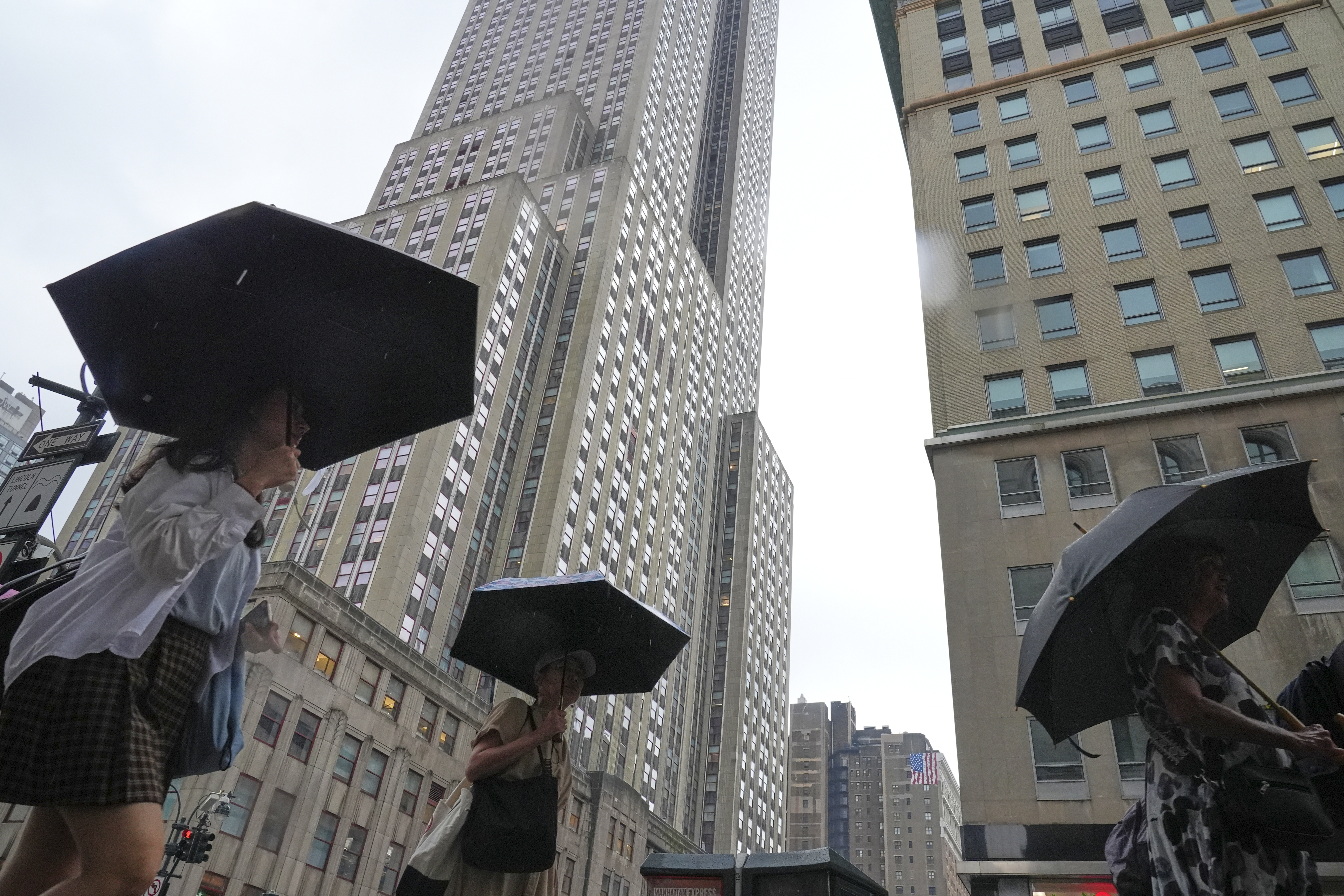 Pedestrians use umbrellas as they pass the Empire State Building during a rain storm Thursday, July 31, 2025, in New York. (AP Photo/Frank Franklin II)