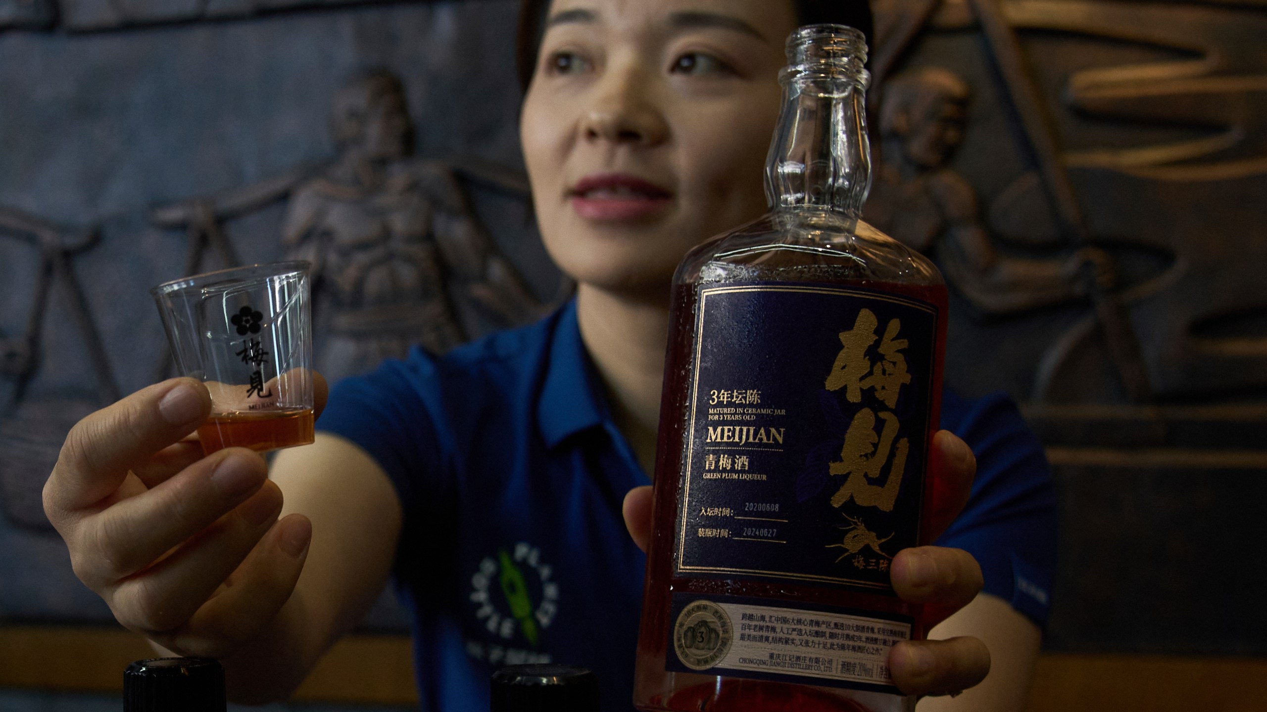 A worker shows the Green Plum Liqueur, a mix handcrafted single sorghum baijiu with plum juice to reporters during a media organized tour at Jiangxiaobai Liquor Co.'s Jiangji Distillery in southwestern China's Chongqing on May 19, 2025. (AP Photo/Andy Wong)