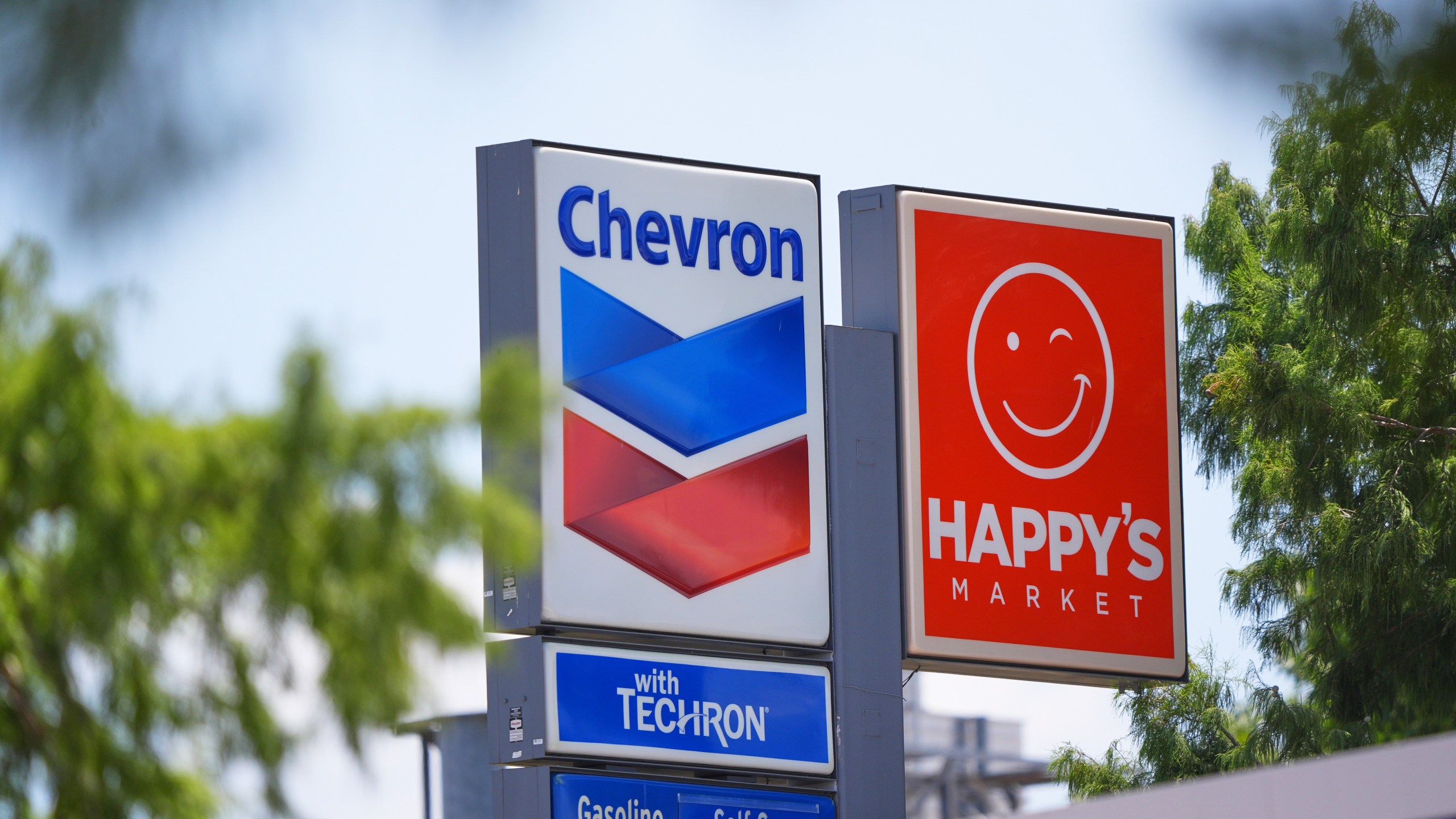 Chevron and Happy's Market signs are shown in Dallas, Tuesday, July 29, 2025. (AP Photo/LM Otero)