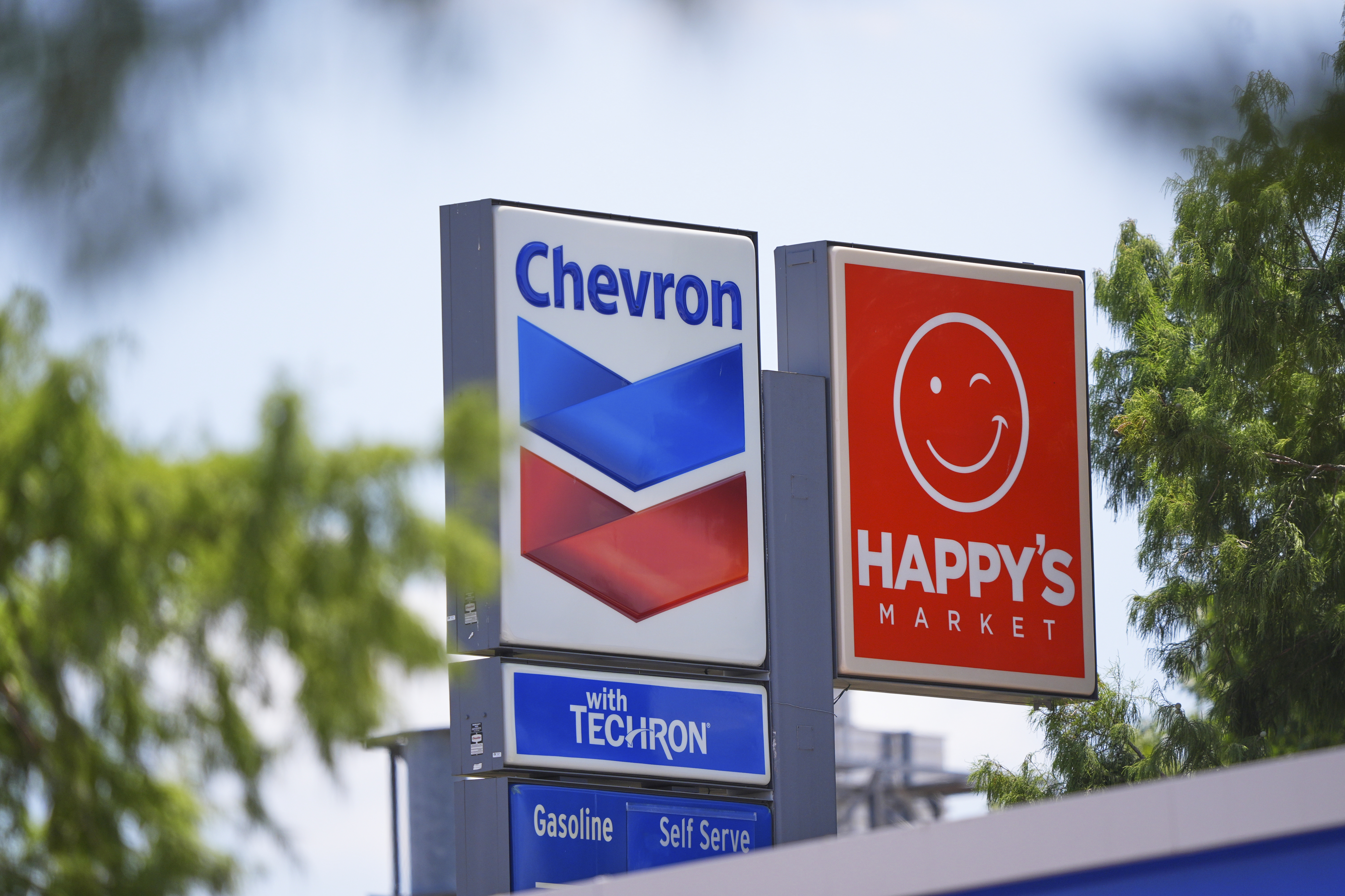 Chevron and Happy's Market signs are shown in Dallas, Tuesday, July 29, 2025. (AP Photo/LM Otero)