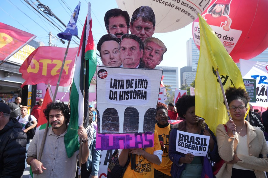Demonstrators carry a sign that reads in Portuguese "The trash can of history, together" and photos of U.S. President Donald Trump, Elon Musk, Sao Paulo's Governor Tarcisio de Freitas, Sao Paulo's Mayor Ricardo Nunes and Brazil's former President Jair Bolsonaro during a protest against a 50% U.S. tariff on Brazilian goods outside the U.S. consulate in Sao Paulo, Friday, Aug. 1, 2025. (AP Photo/Andre Penner)