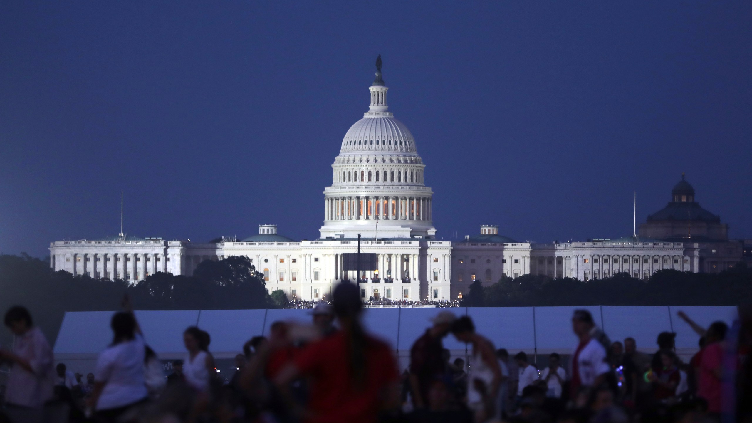 The U.S. Capitol building stands as people wait to watch fireworks near the Washington Monument during Fourth of July celebrations, in Washington, Friday, July 4, 2025. (AP Photo/Rahmat Gul)