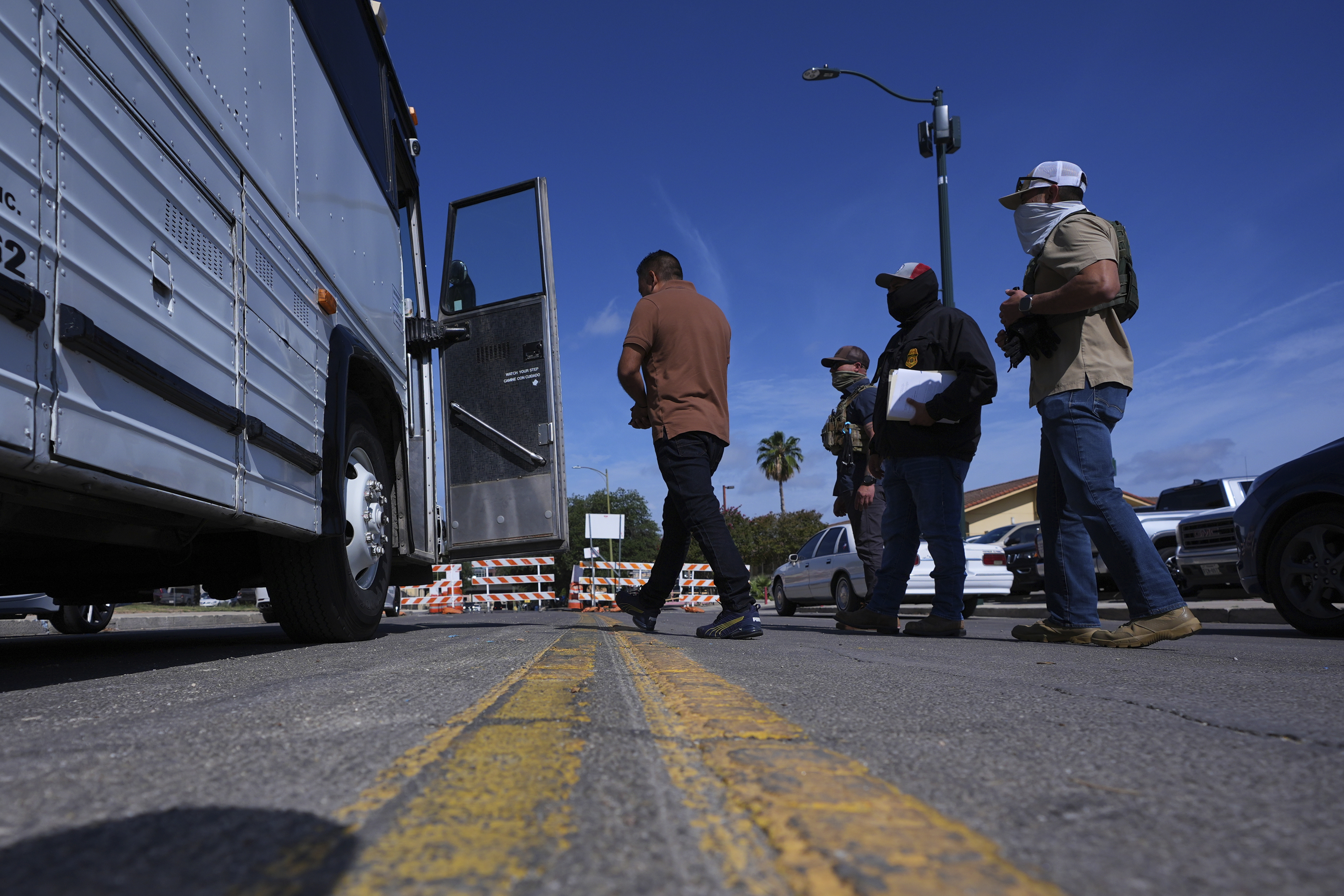 Federal agents escort a man to a transport bus after he was detained following an appearance at immigration court, Tuesday, July 22, 2025, in San Antonio. (AP Photo/Eric Gay)