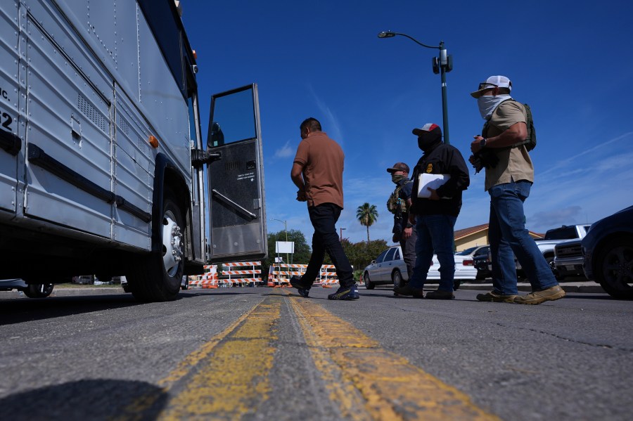 Federal agents escort a man to a transport bus after he was detained following an appearance at immigration court, Tuesday, July 22, 2025, in San Antonio. (AP Photo/Eric Gay)