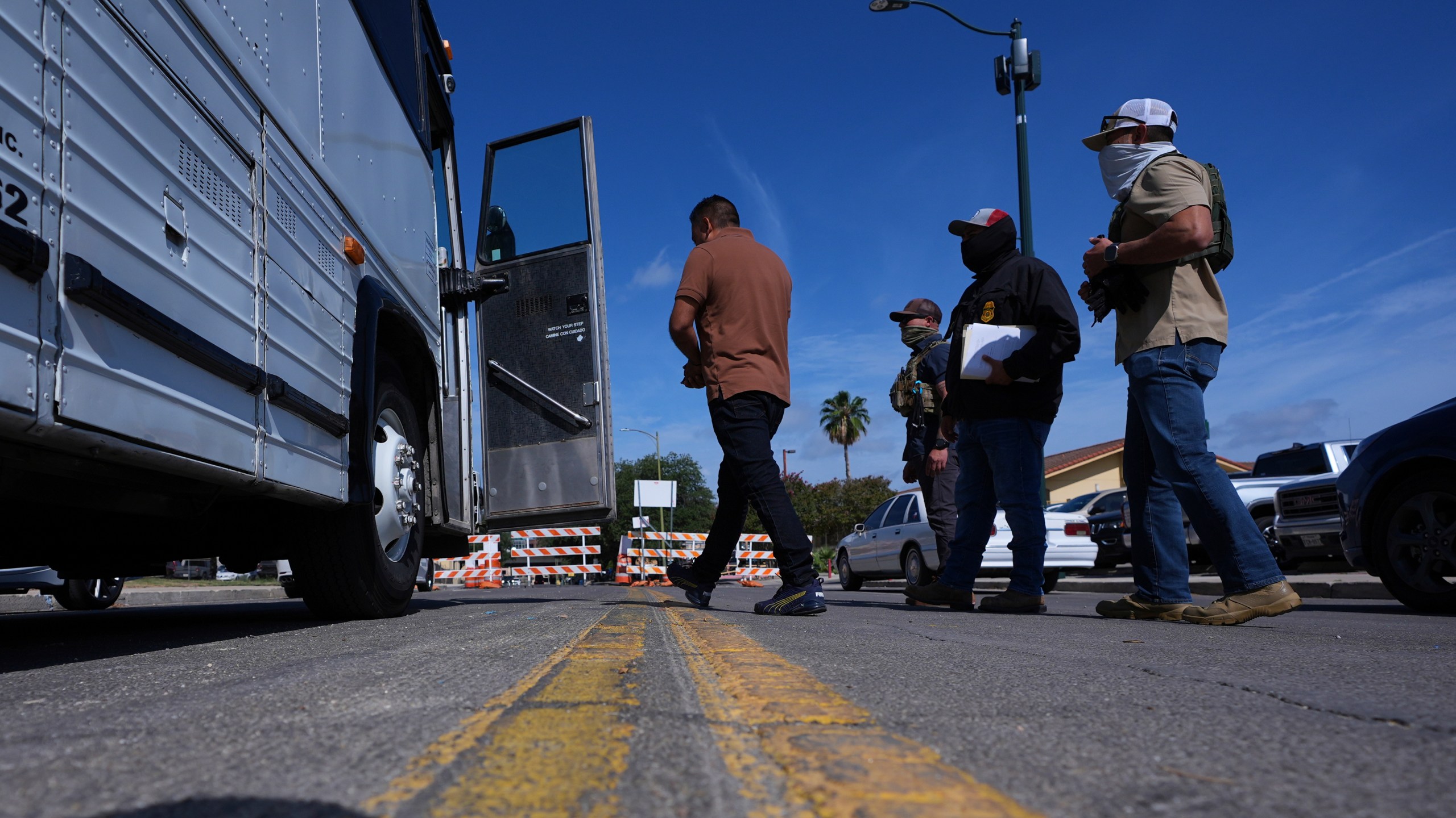 Federal agents escort a man to a transport bus after he was detained following an appearance at immigration court, Tuesday, July 22, 2025, in San Antonio. (AP Photo/Eric Gay)