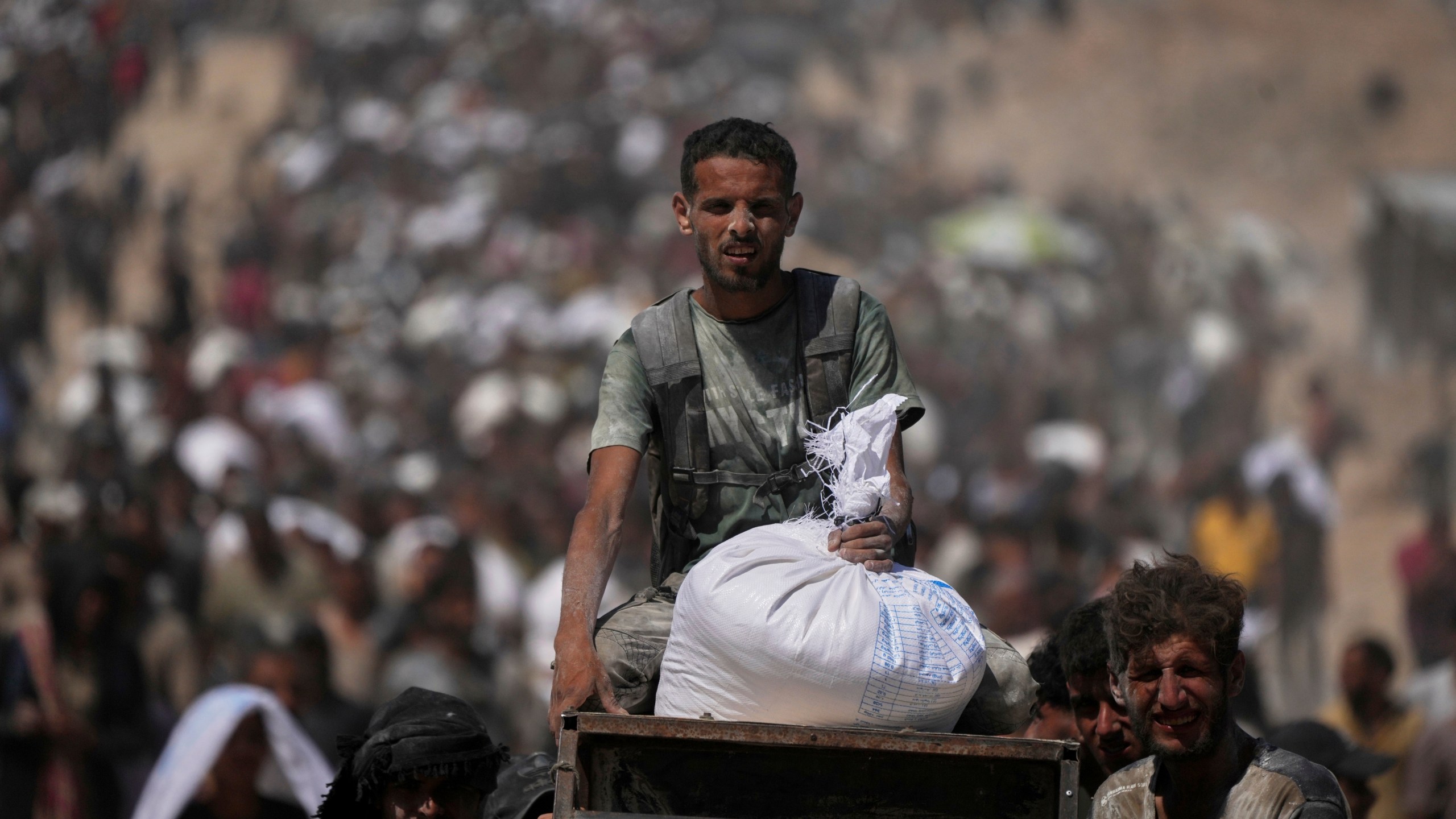 Palestinians carry sacks of flour taken from a humanitarian aid convoy en route to Gaza City, in the outskirts of Beit Lahiya, northern Gaza Strip, Friday, Aug. 1, 2025. (AP Photo/Jehad Alshrafi)