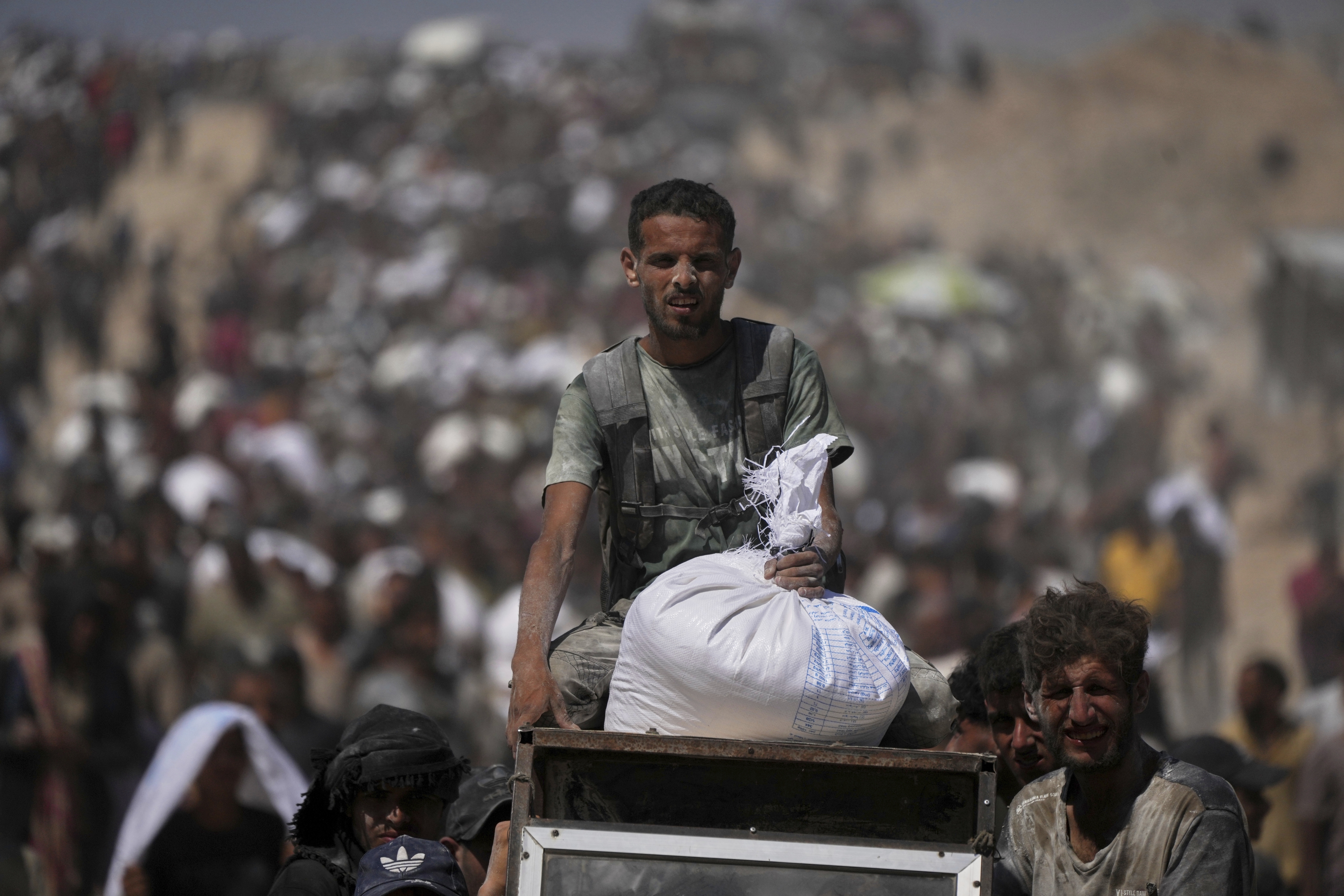 Palestinians carry sacks of flour taken from a humanitarian aid convoy en route to Gaza City, in the outskirts of Beit Lahiya, northern Gaza Strip, Friday, Aug. 1, 2025. (AP Photo/Jehad Alshrafi)