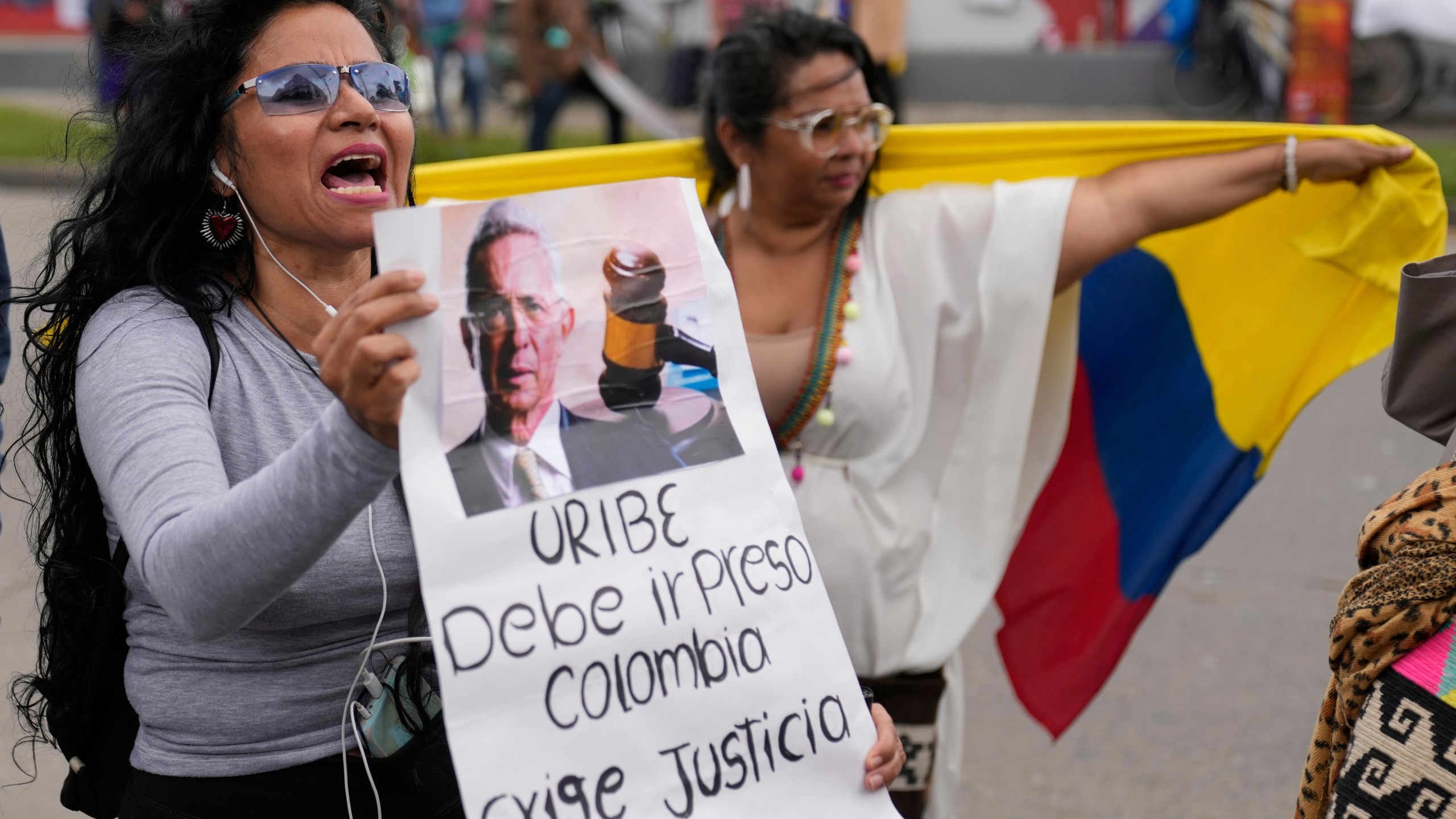Opponents of former President Alvaro Uribe gather outside the court on the day he was sentenced to 12 years under house arrest for witness tampering and bribery in Bogota, Colombia, Friday, Aug. 1, 2025. (AP Photo/Fernando Vergara)