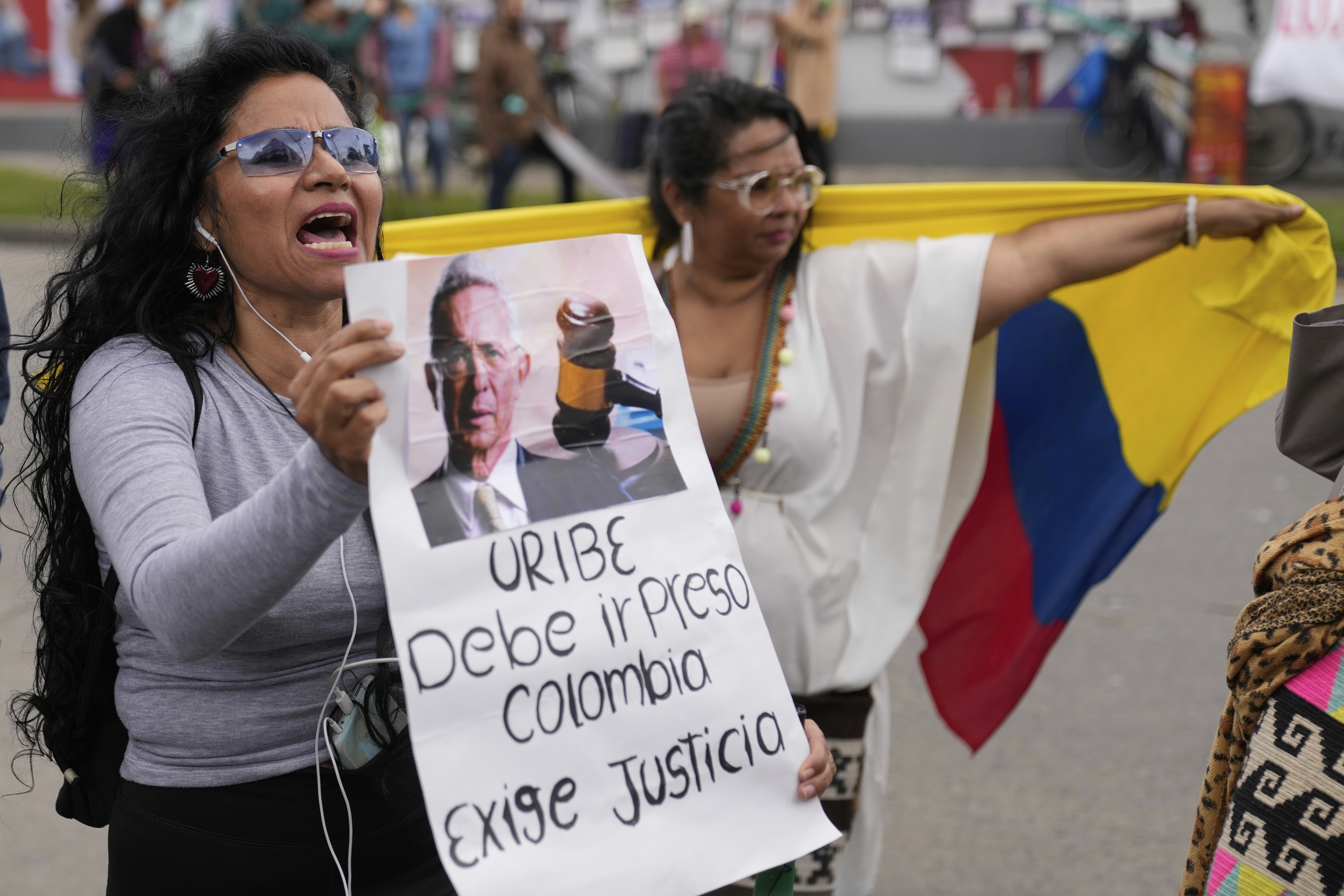 Opponents of former President Alvaro Uribe gather outside the court on the day he was sentenced to 12 years under house arrest for witness tampering and bribery in Bogota, Colombia, Friday, Aug. 1, 2025. (AP Photo/Fernando Vergara)