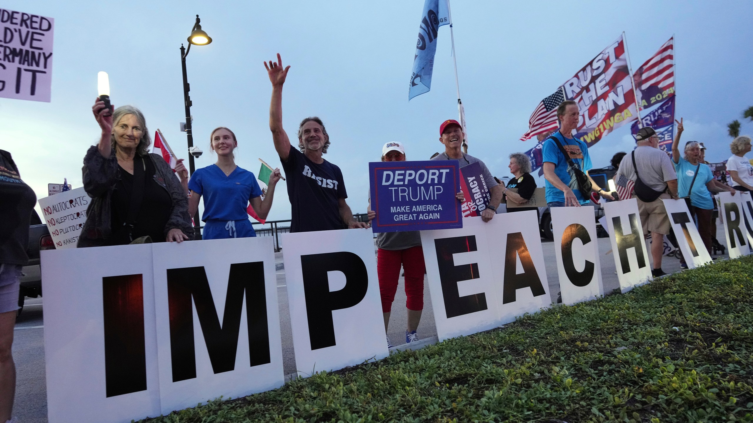 Protesters display signs reading "Impeach Trump," during a rally near President Donald Trump's Mar-a-Lago estate in Palm Beach, Fla., as part of the "Good Trouble Lives On" national day of action, Thursday, July 17, 2025. (AP Photo/Rebecca Blackwell)