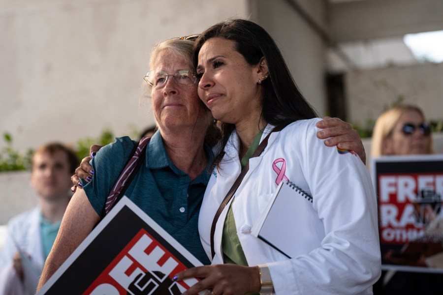 Dr. Wafaa Alrashid, right, whose husband, Rami Othmane, a Tunisian musician, is detained at the U.S. Immigration and Customs Enforcement facility, is comforted by Dr. Kimberly Shriner during a rally outside the facility in Los Angeles Friday, July 25, 2025. (AP Photo/Jae C. Hong)