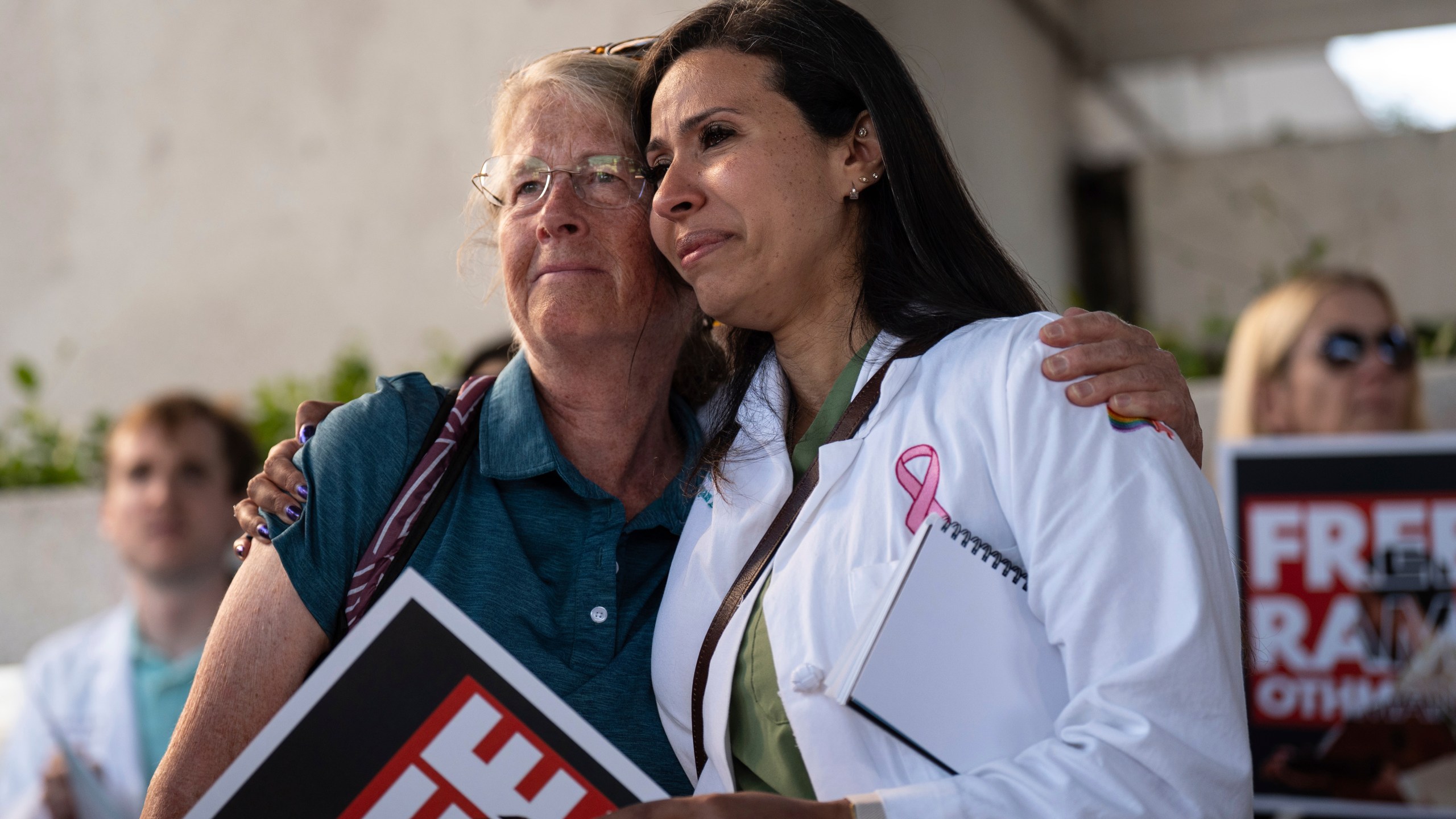 Dr. Wafaa Alrashid, right, whose husband, Rami Othmane, a Tunisian musician, is detained at the U.S. Immigration and Customs Enforcement facility, is comforted by Dr. Kimberly Shriner during a rally outside the facility in Los Angeles Friday, July 25, 2025. (AP Photo/Jae C. Hong)