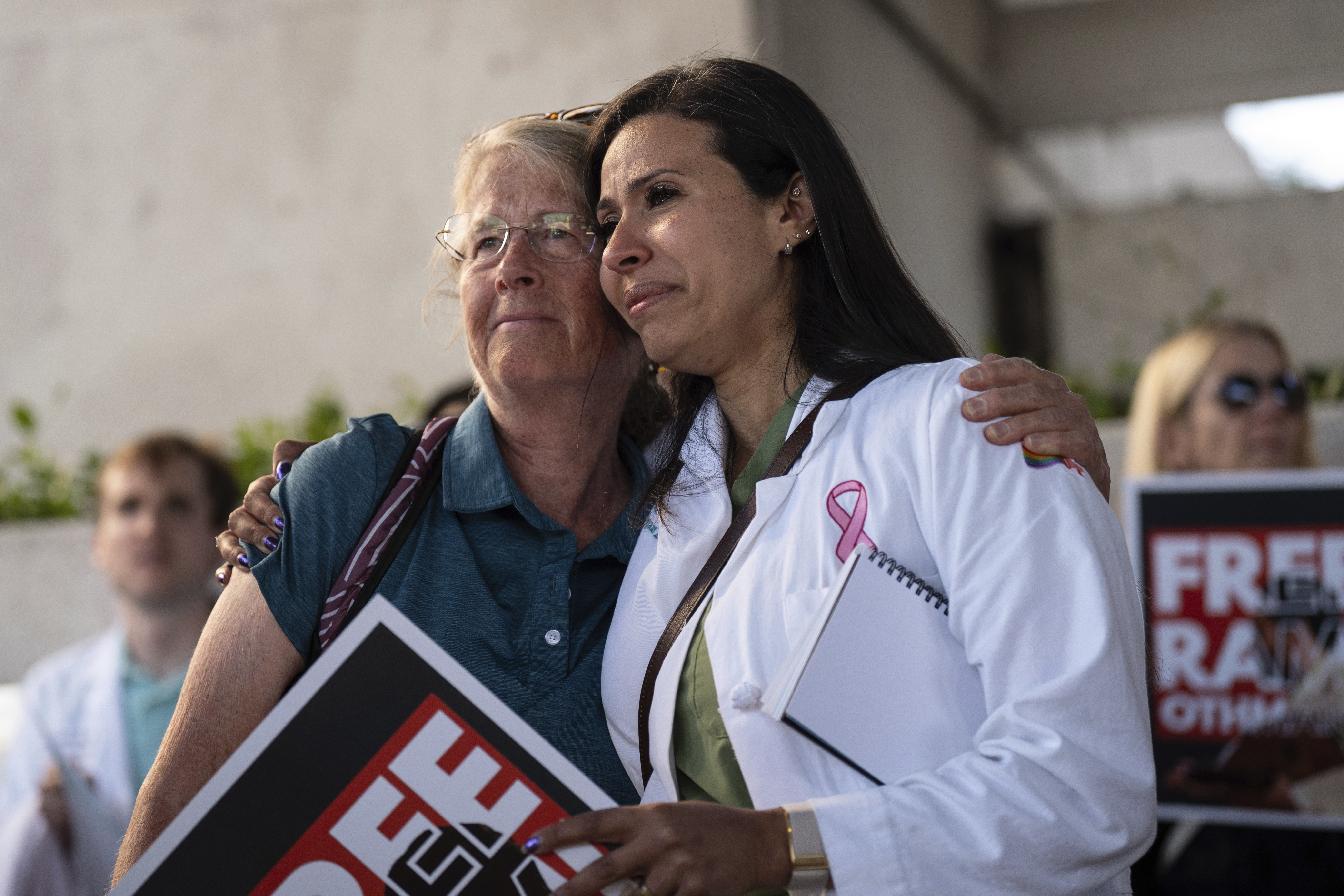 Dr. Wafaa Alrashid, right, whose husband, Rami Othmane, a Tunisian musician, is detained at the U.S. Immigration and Customs Enforcement facility, is comforted by Dr. Kimberly Shriner during a rally outside the facility in Los Angeles Friday, July 25, 2025. (AP Photo/Jae C. Hong)