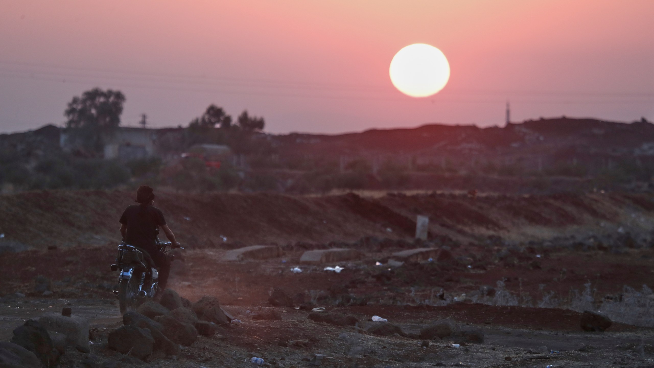 A Bedouin fighter rides a motorcycle as the sun sets over the village of Busra al-Harir, southern Syria, Tuesday, July 22, 2025. (AP Photo/Omar Sanadiki)