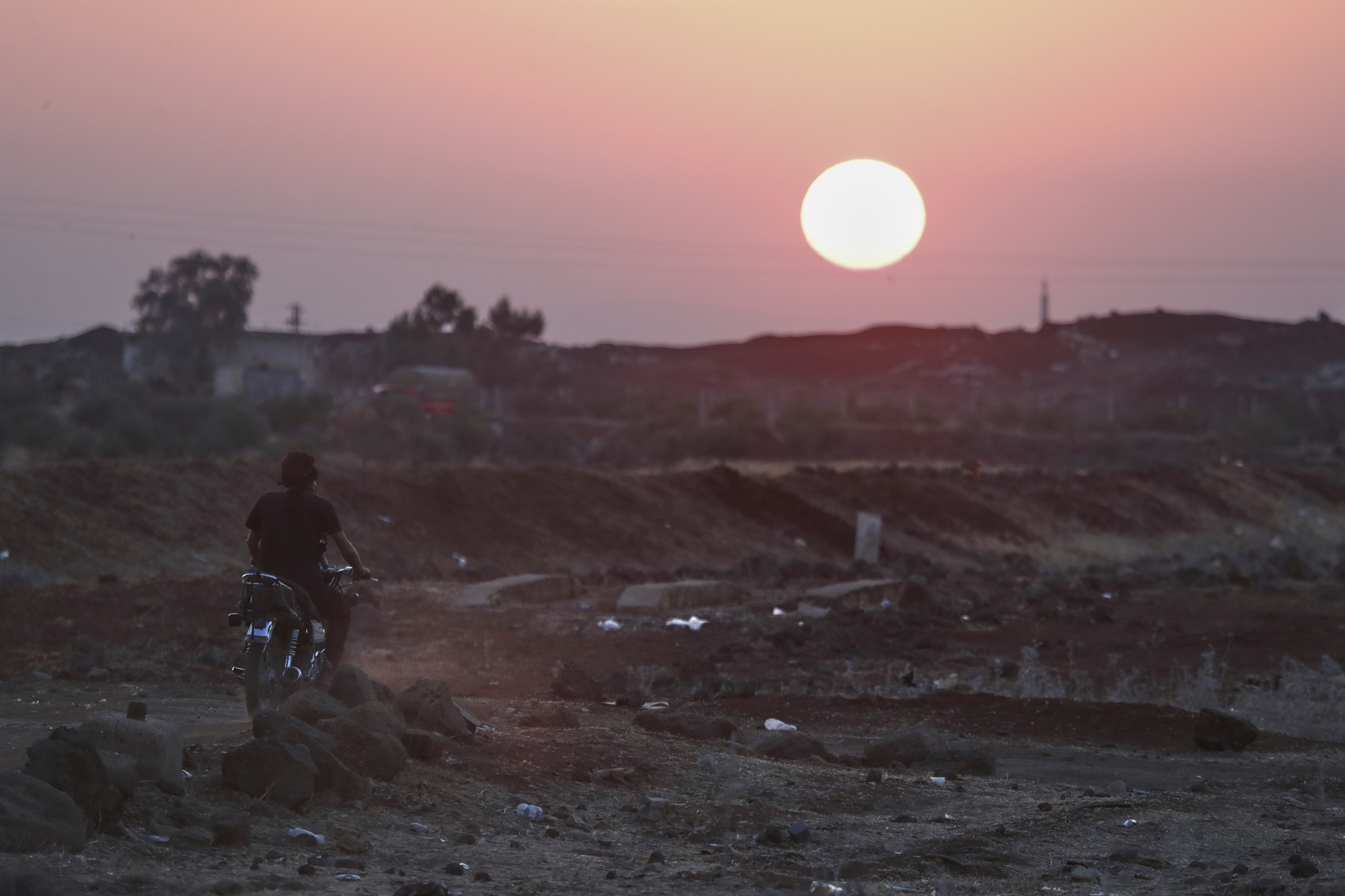 A Bedouin fighter rides a motorcycle as the sun sets over the village of Busra al-Harir, southern Syria, Tuesday, July 22, 2025. (AP Photo/Omar Sanadiki)